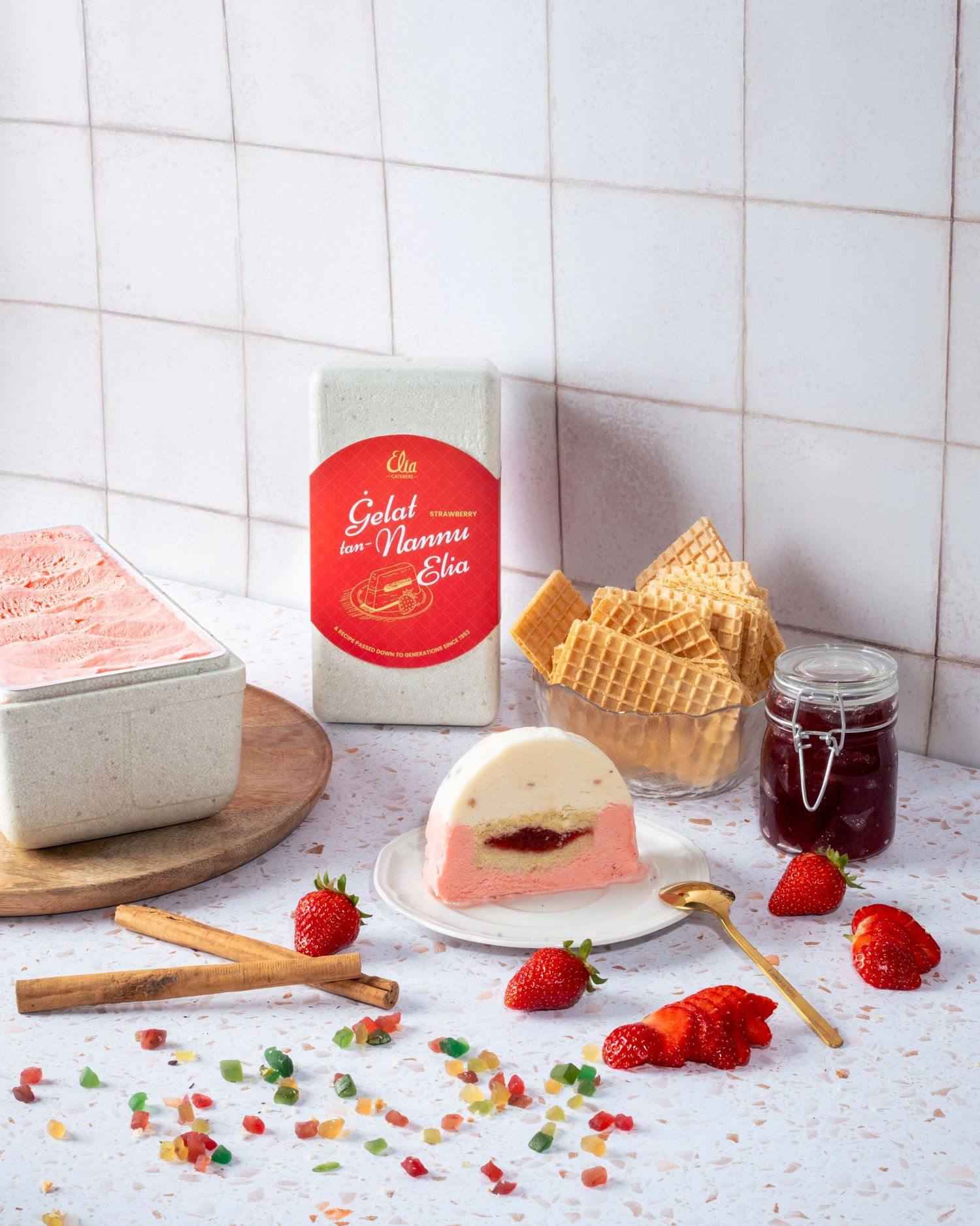 Elegant dessert presentation with strawberries, cake slices and jam on a tiled surface.