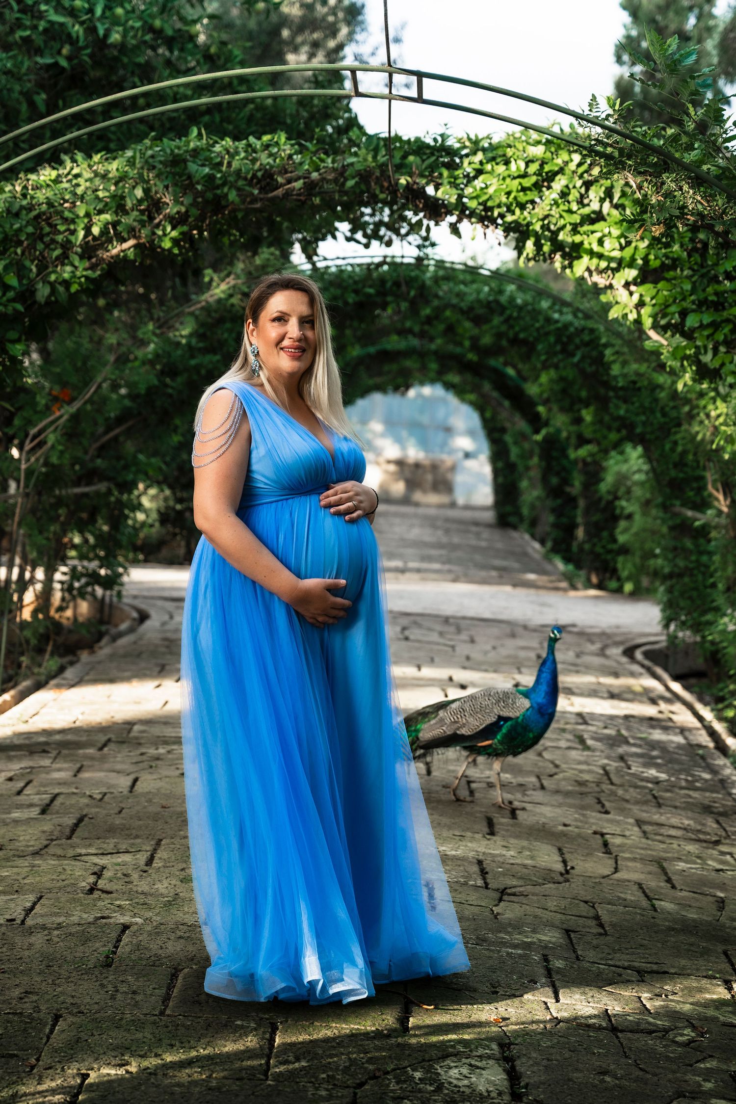 Elegant blue gown session on stone pathway under garden archway.