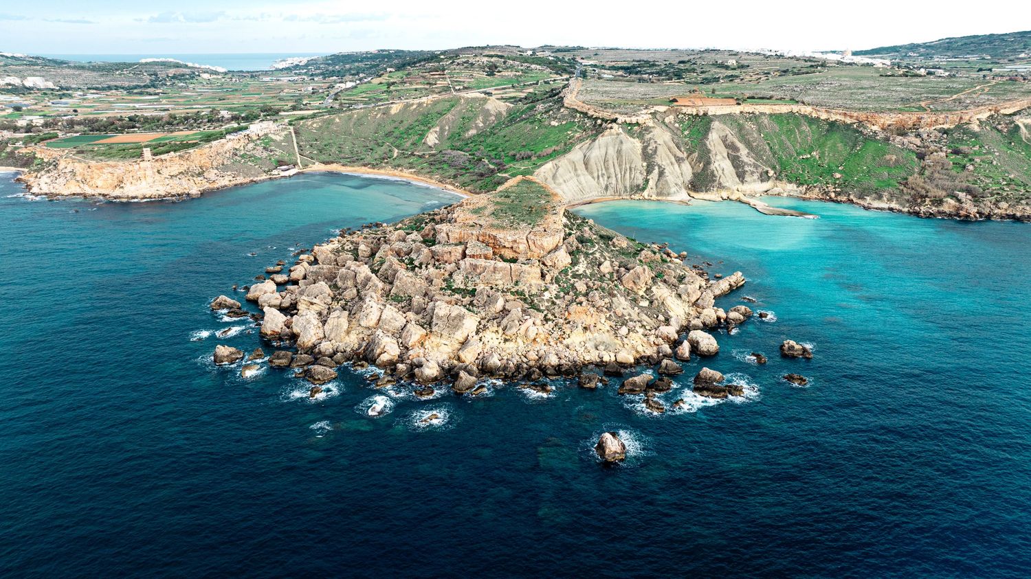 Panoramic view of rugged coastal cliffs and turquoise Mediterranean waters along a scenic shoreline.