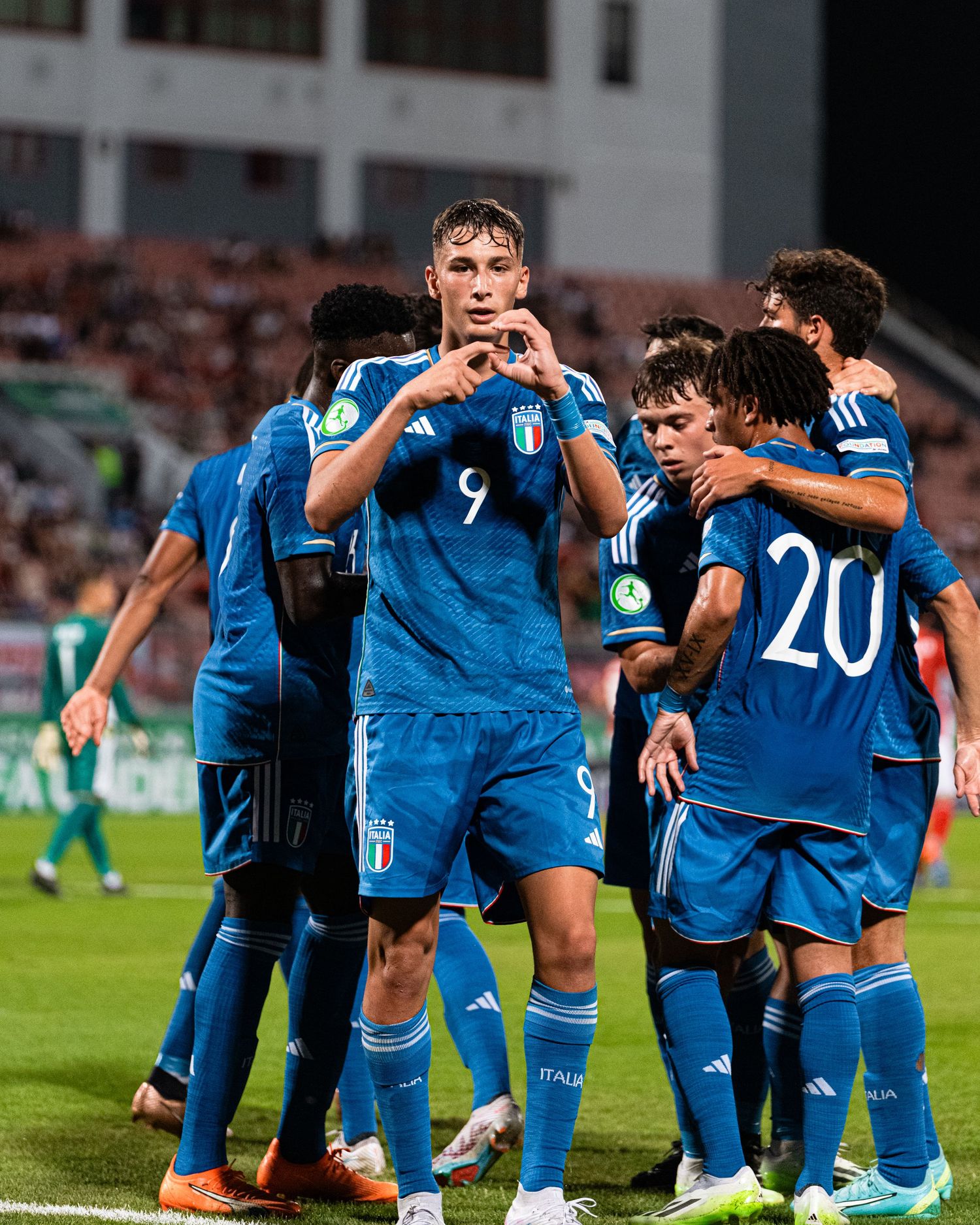 Soccer team players in blue jerseys celebrating together on the field during a match.