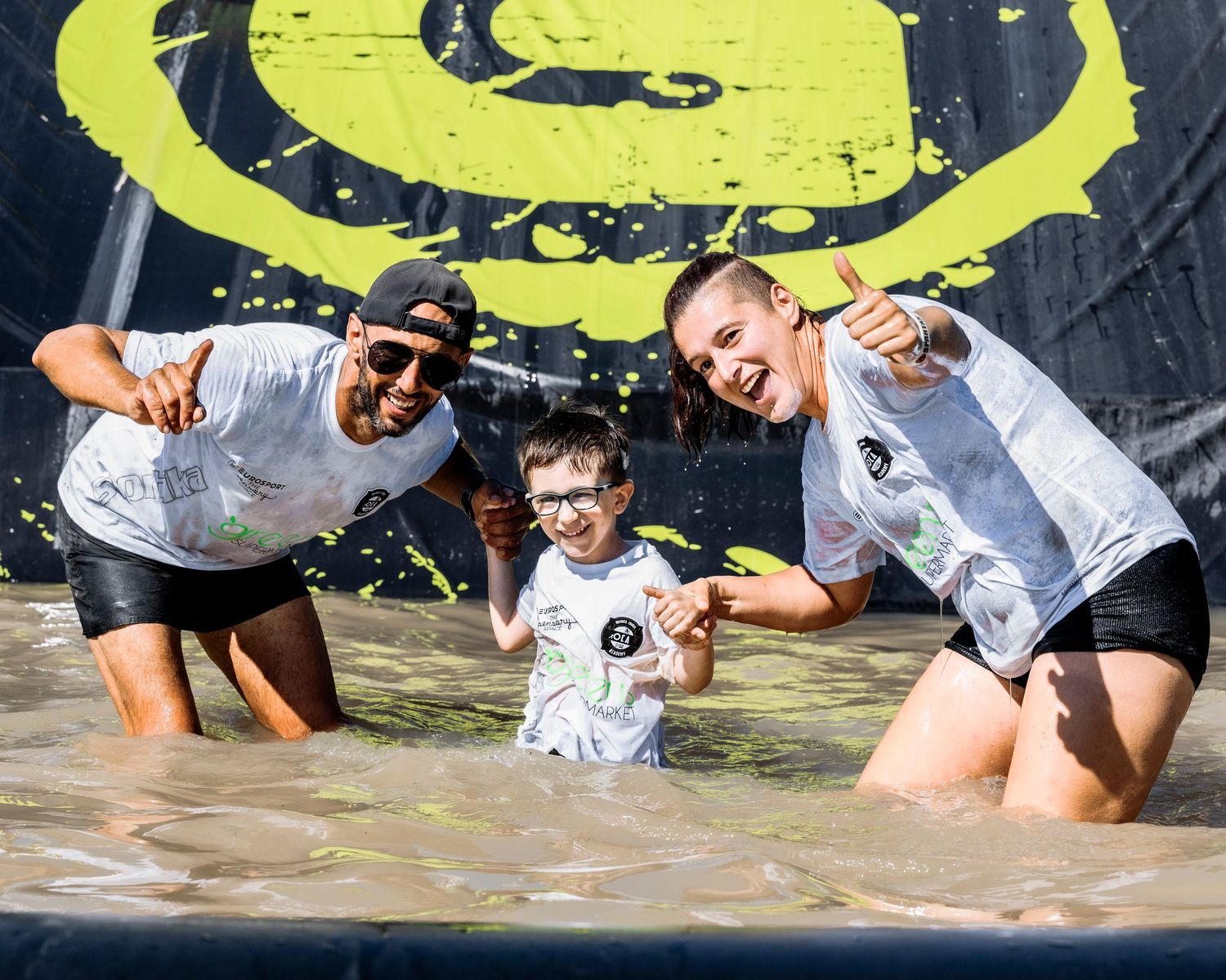Participants crawling under obstacles during a muddy race challenge.