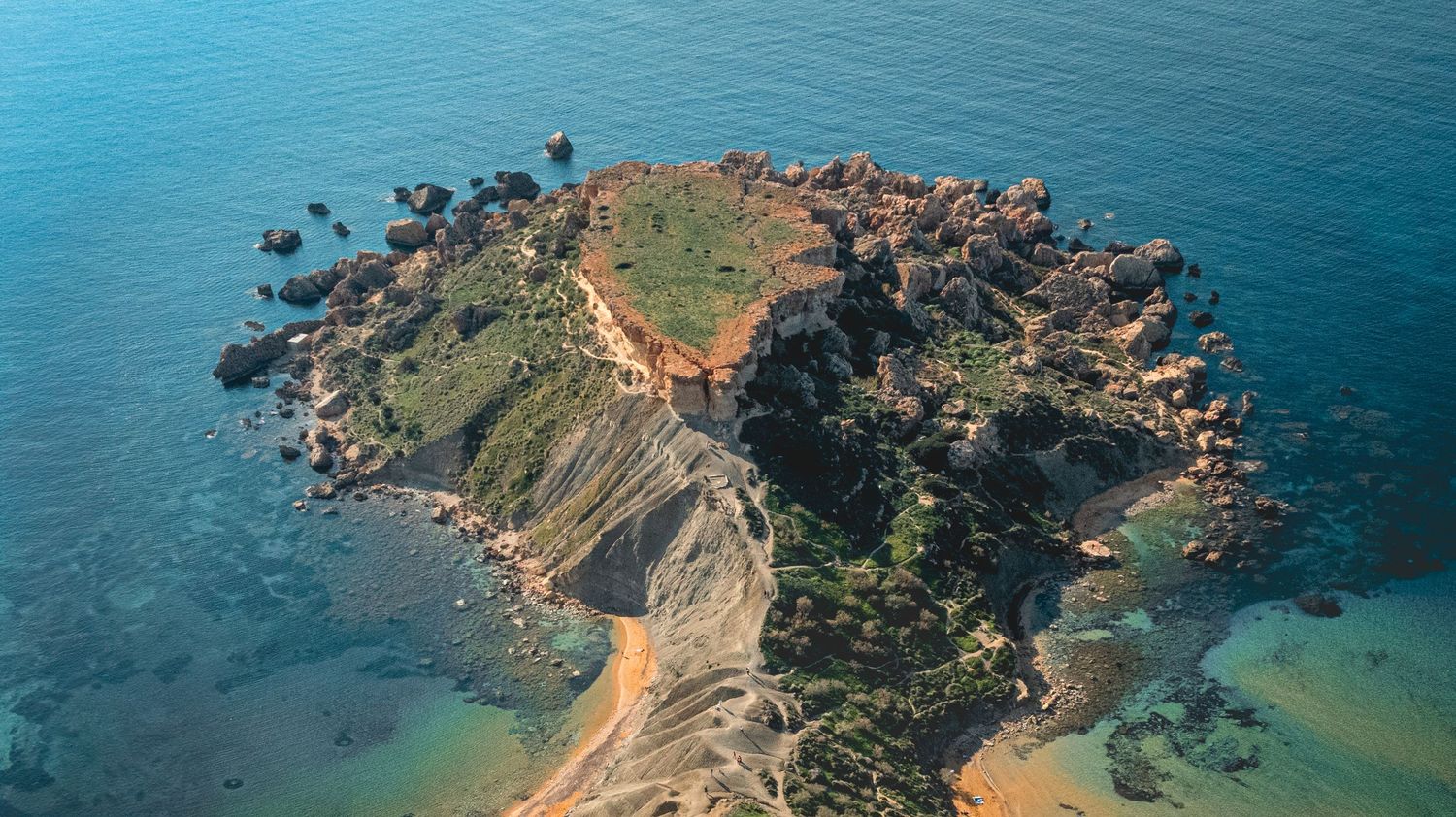 Aerial panorama of pristine beaches and rocky outcrops surrounded by crystal-clear turquoise waters.