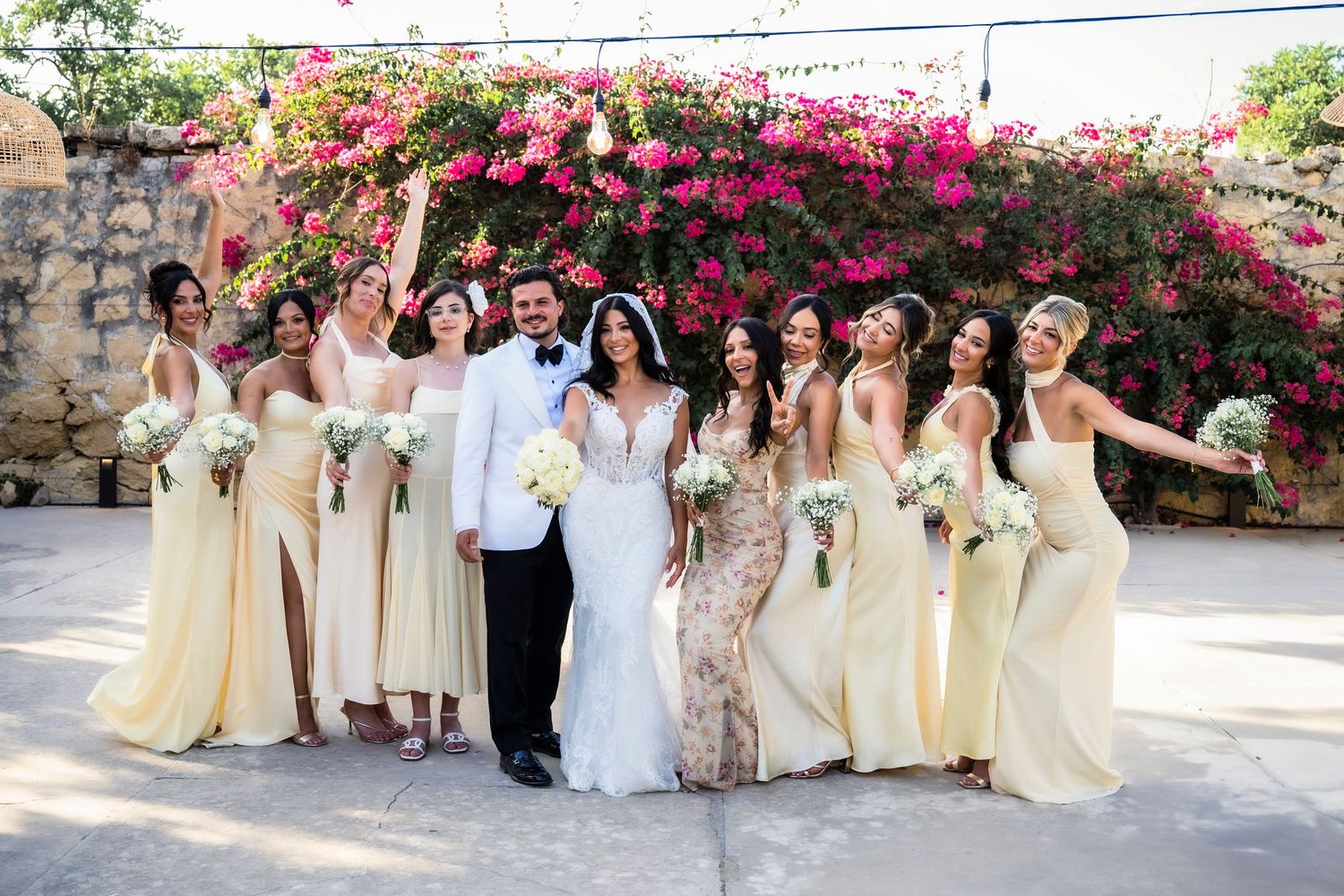 Wedding party posing together against vibrant pink bougainvillea flowers.