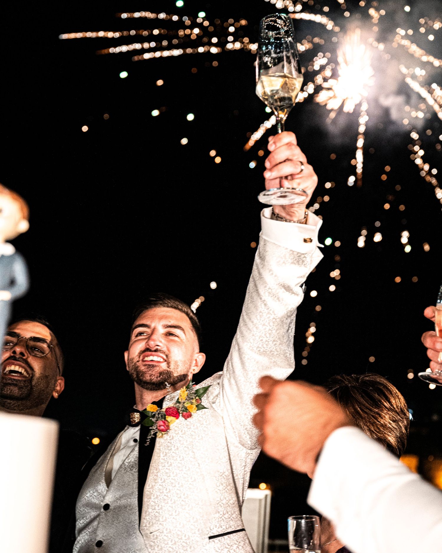 Celebratory moment with sparklers illuminating the night as guests raise their glasses.