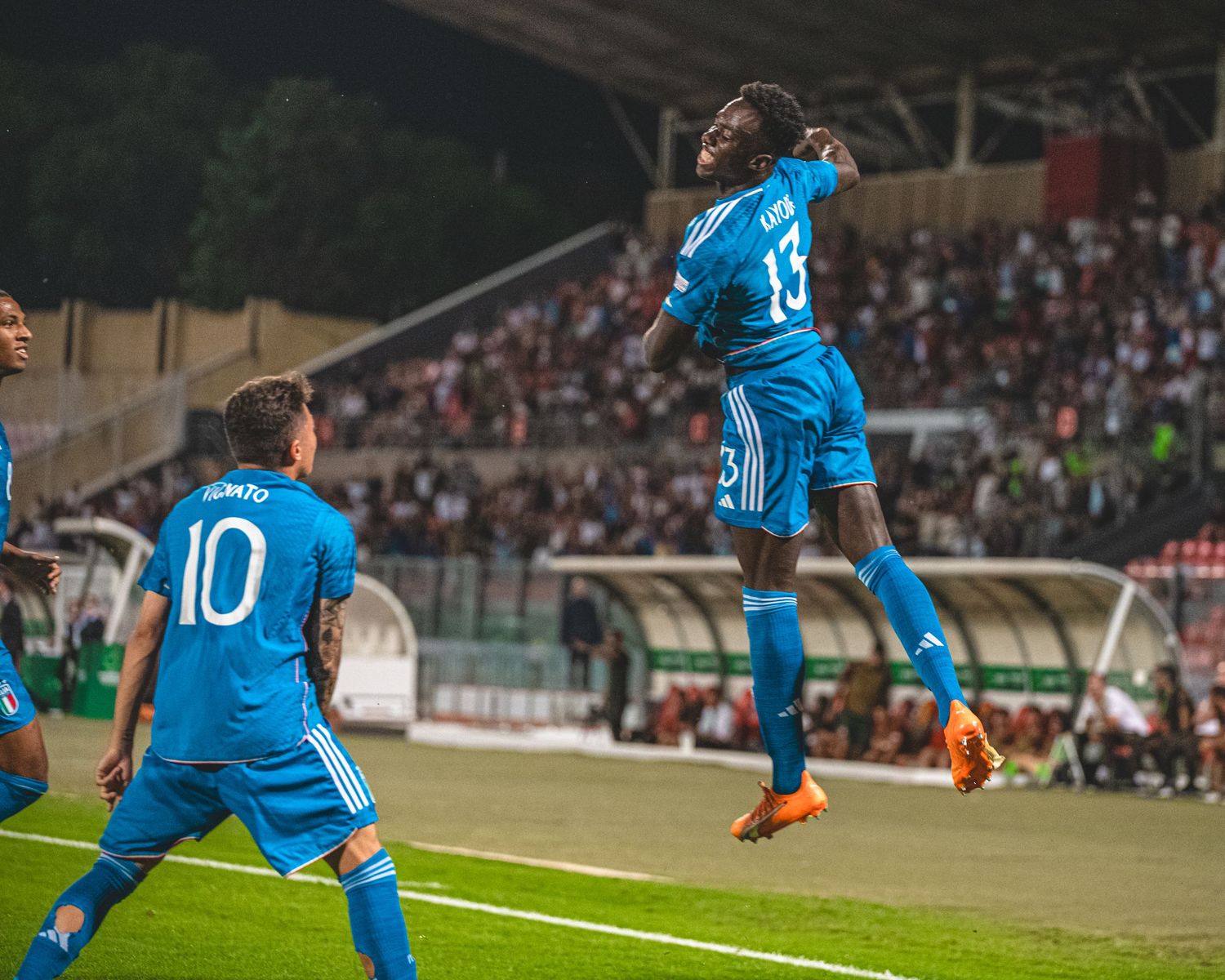 Soccer players in blue jerseys running on field during competitive match.