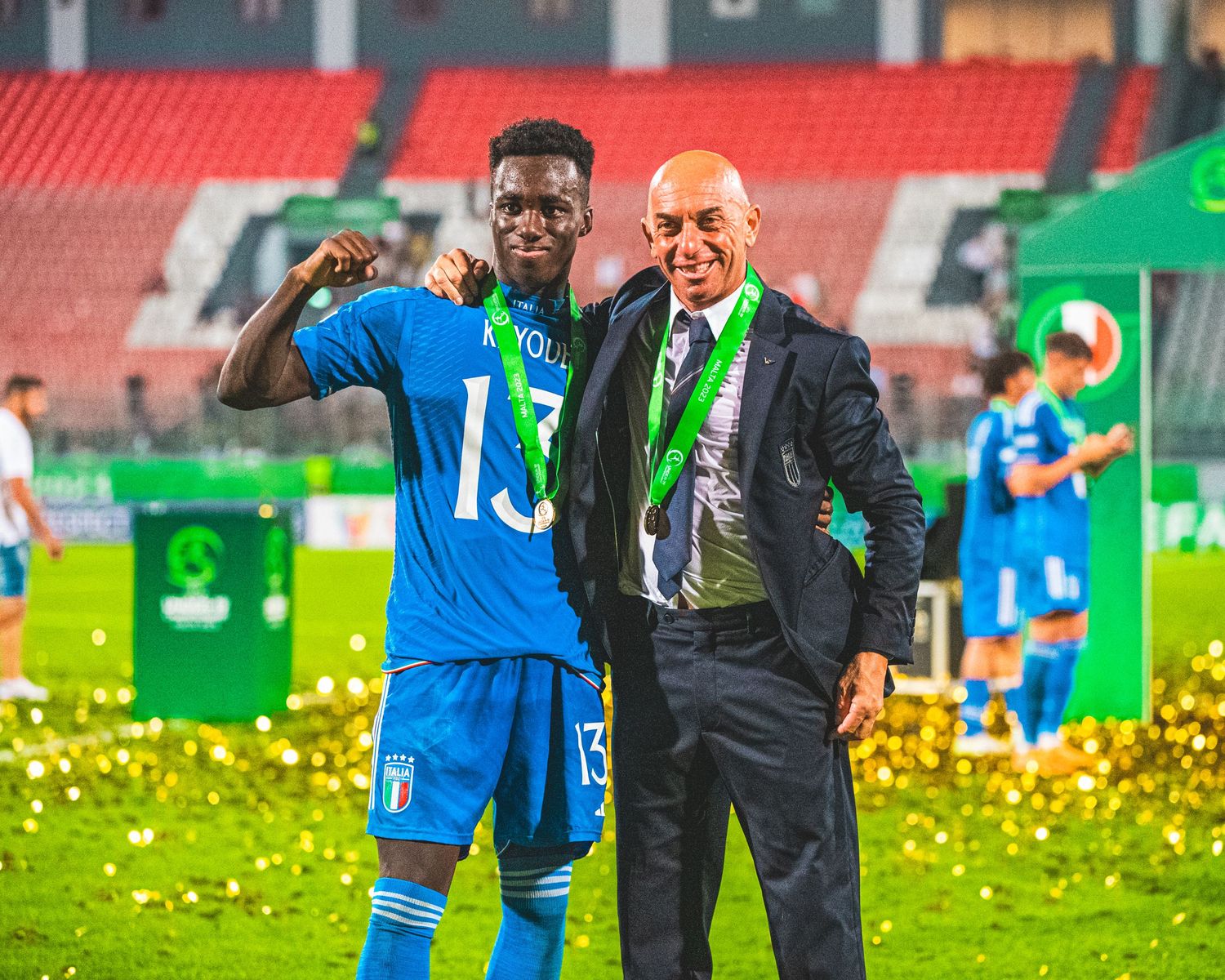Soccer team celebrating victory with confetti and trophies on a stadium field.