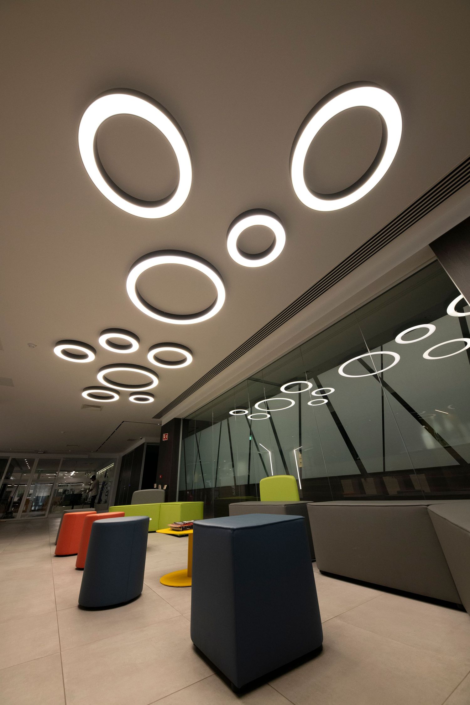 Contemporary lounge area with circular LED ceiling lights and geometric seating in bold colors.
