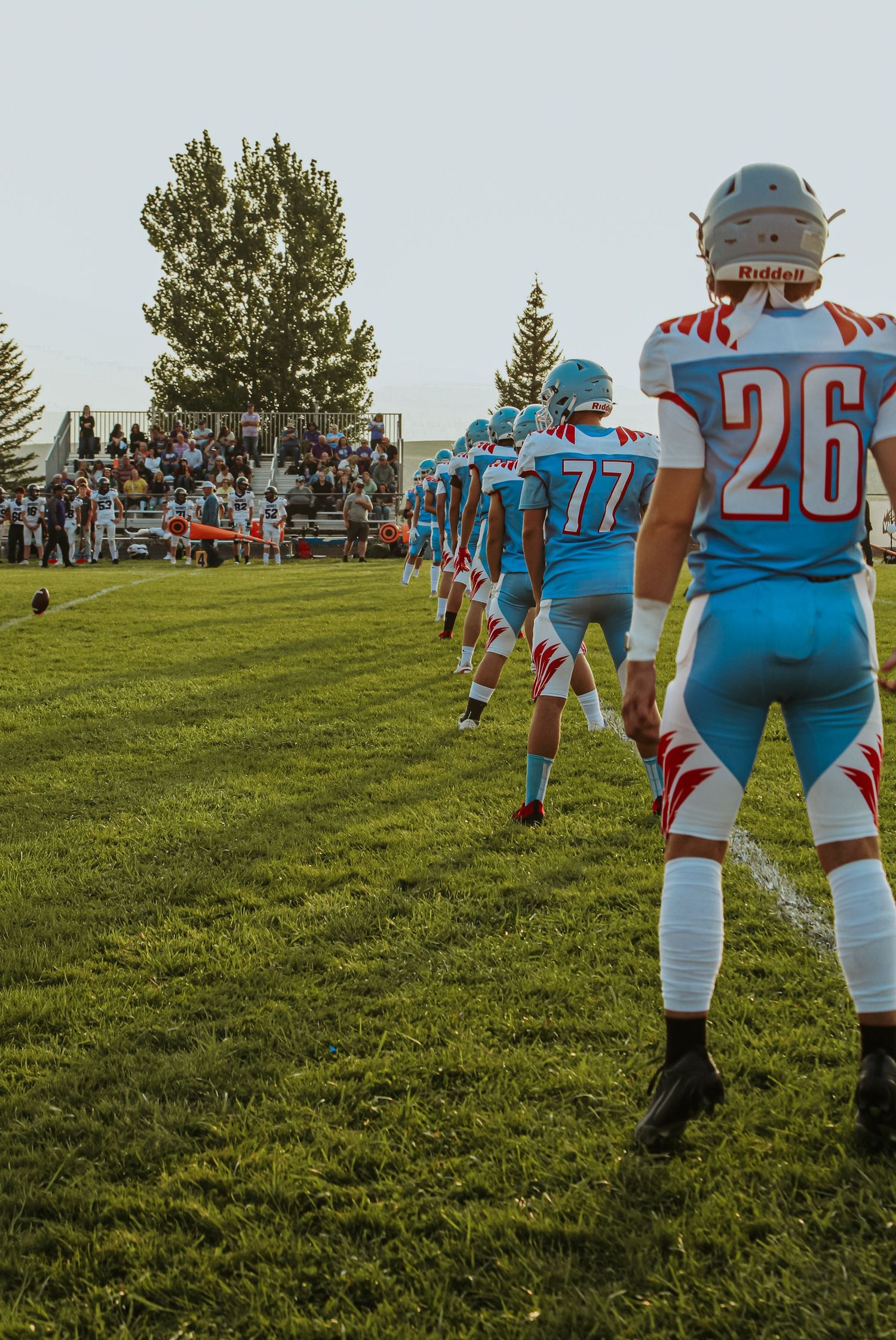 Football players in light blue uniforms warming up on grassy field.