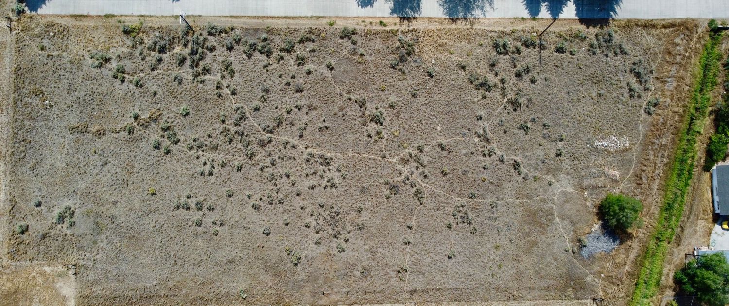 Aerial view of a barren field with scattered dark spots across the terrain.