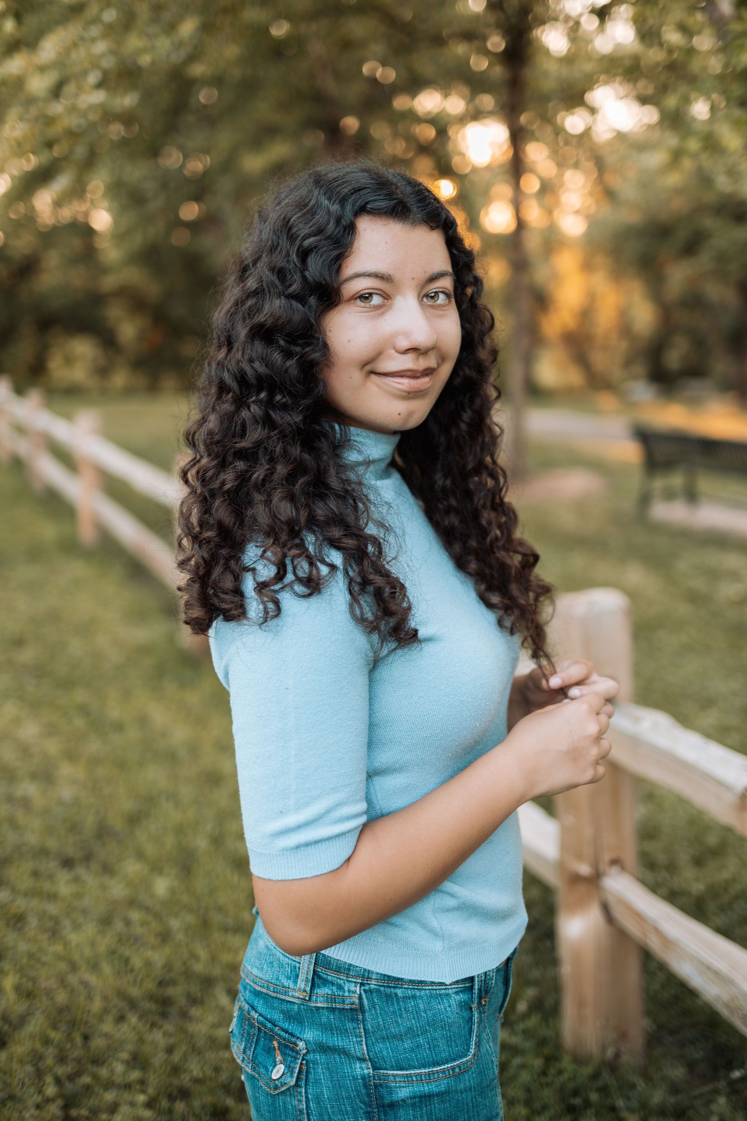 Sunset portrait session by wooden fence wearing light blue top and denim with Kenzie Ayla Images in the Twin Cities MN area.