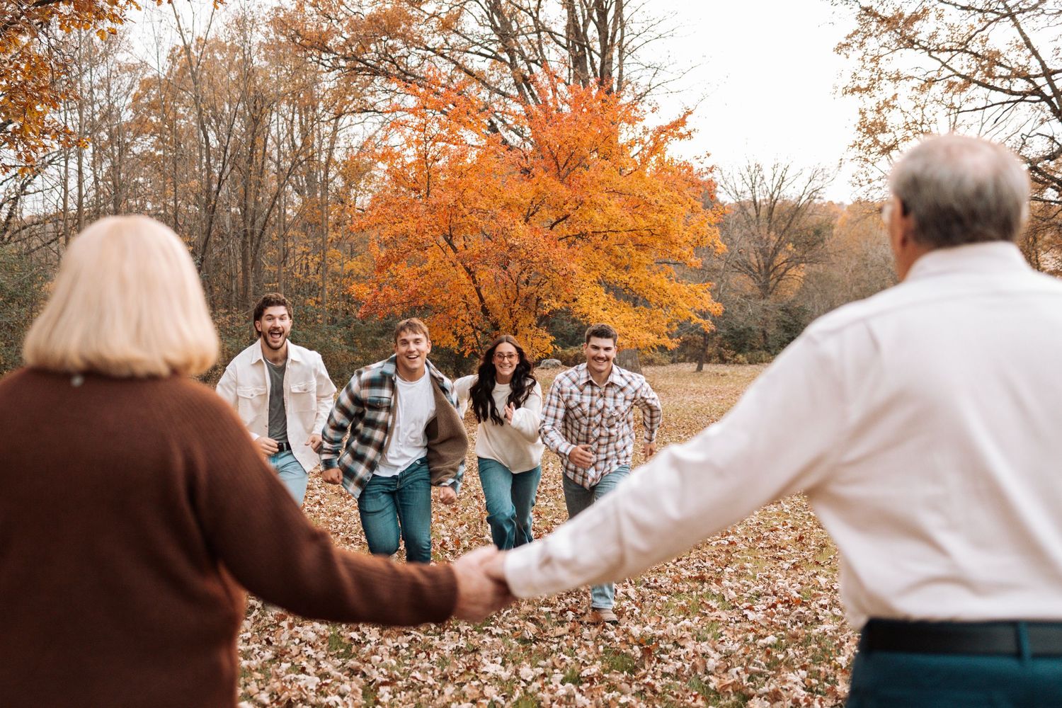 Candid family moments captured during a fall photoshoot with orange foliage in background.