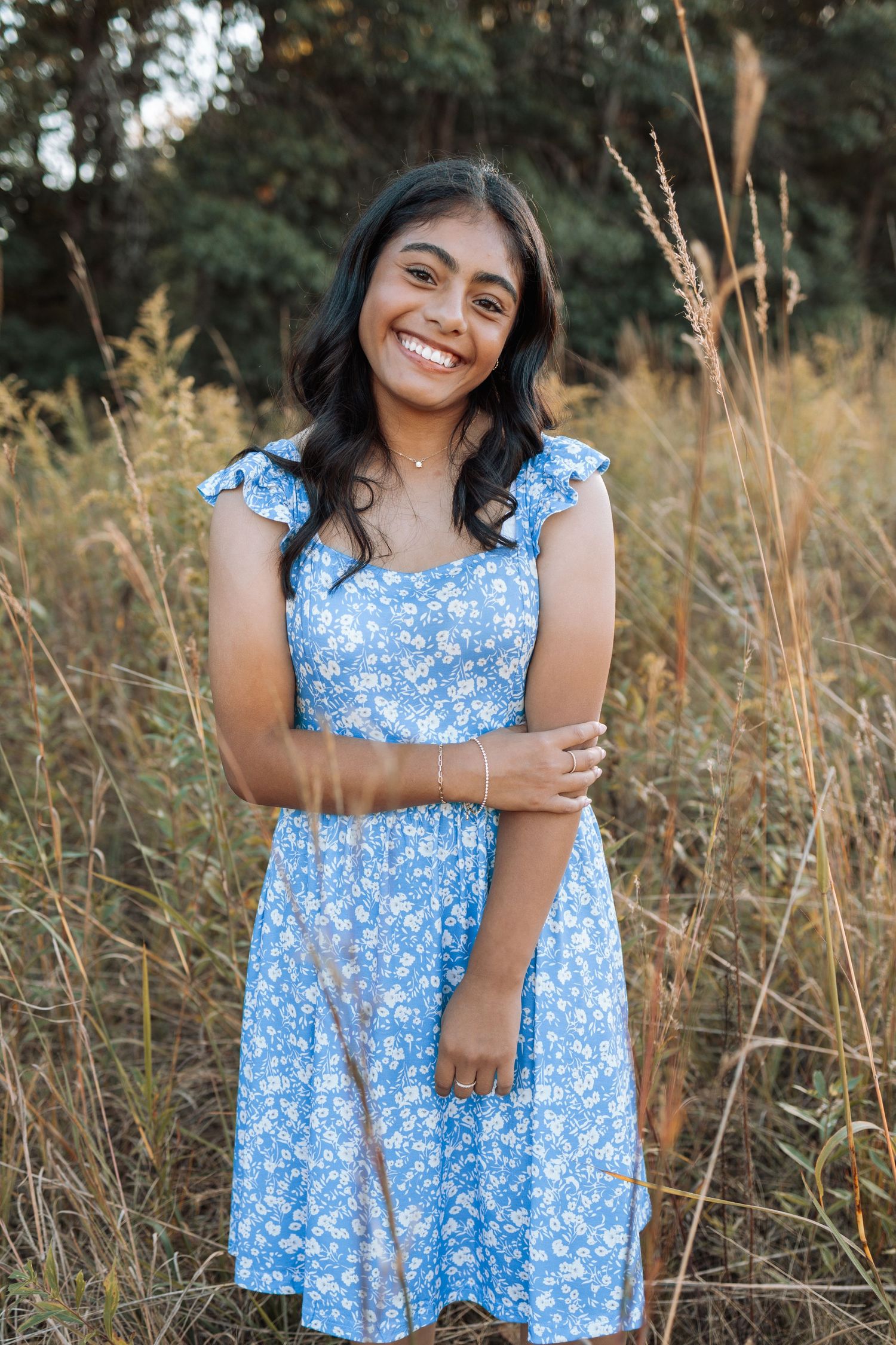 Woman in blue floral dress poses in golden field at sunset with Kenzie Ayla Images in the Twin Cities MN area.