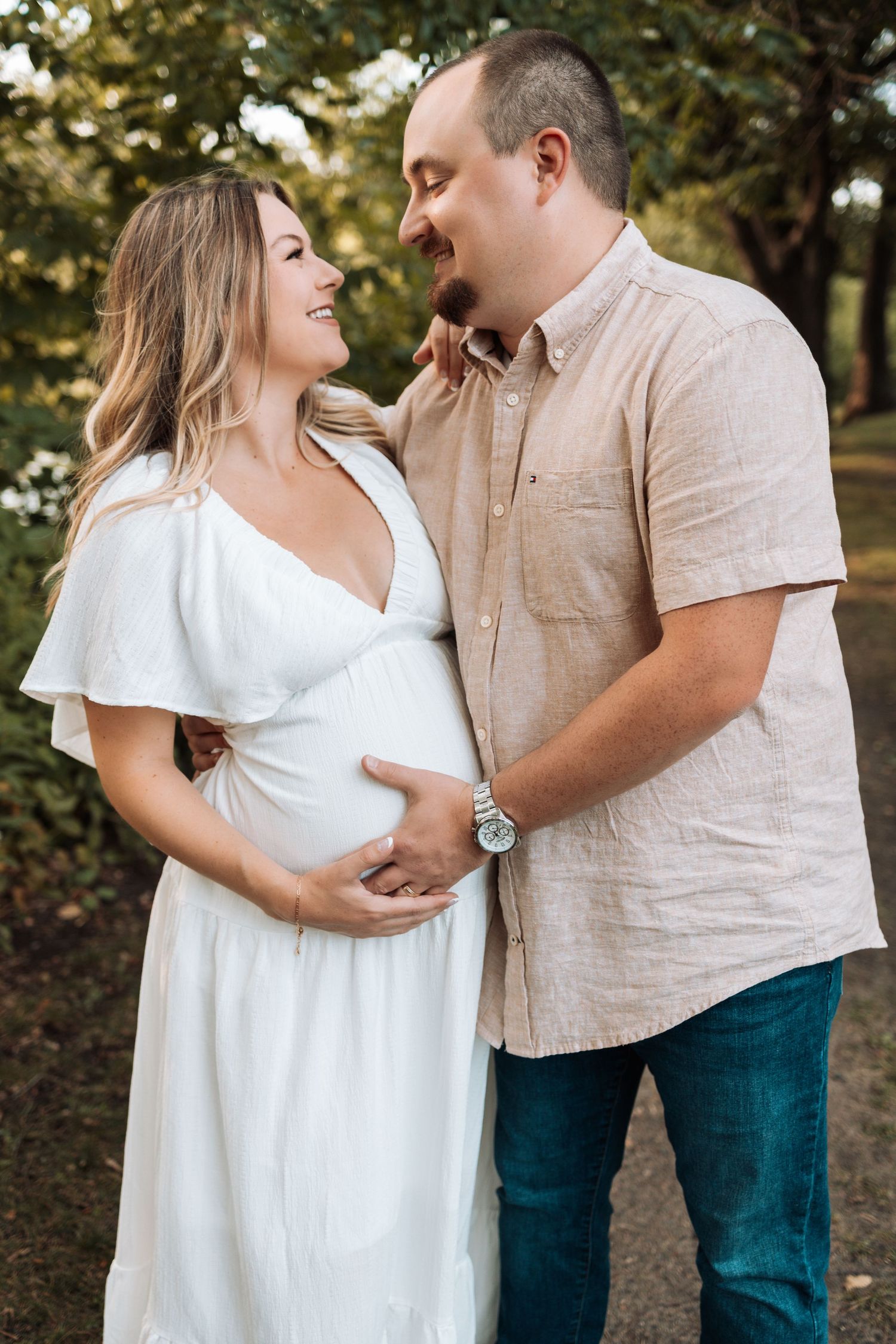 Couple in white and beige clothing share romantic moments during an outdoor photo session.