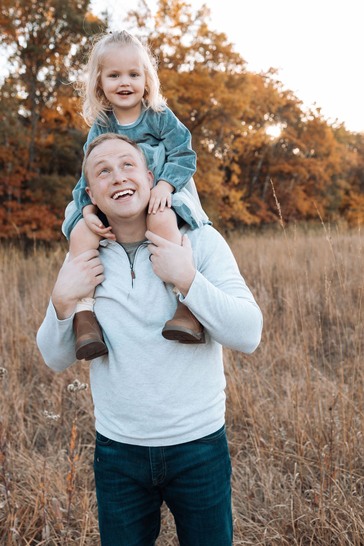 Playful piggyback ride moment captured in a fall field with warm lighting.