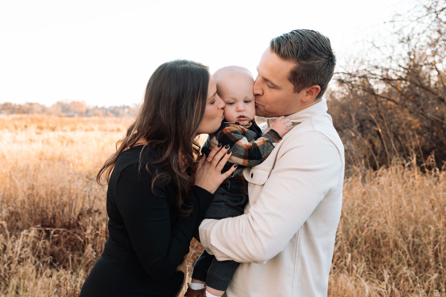 Warm autumn family photoshoot in a golden field at sunset.