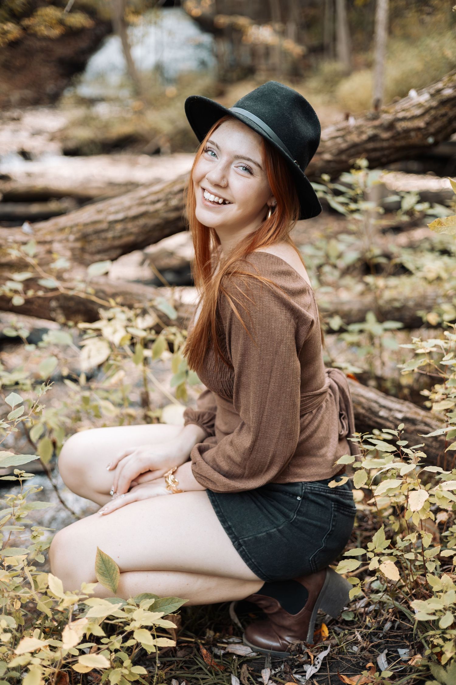 Casual autumn portrait sitting by fallen logs in nature with Kenzie Ayla Images in the Twin Cities MN area.