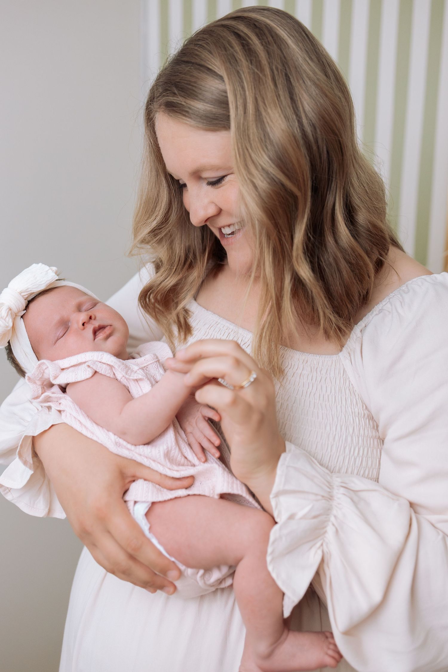 Mother in white sweater holding and bonding with newborn baby wearing pink outfit.