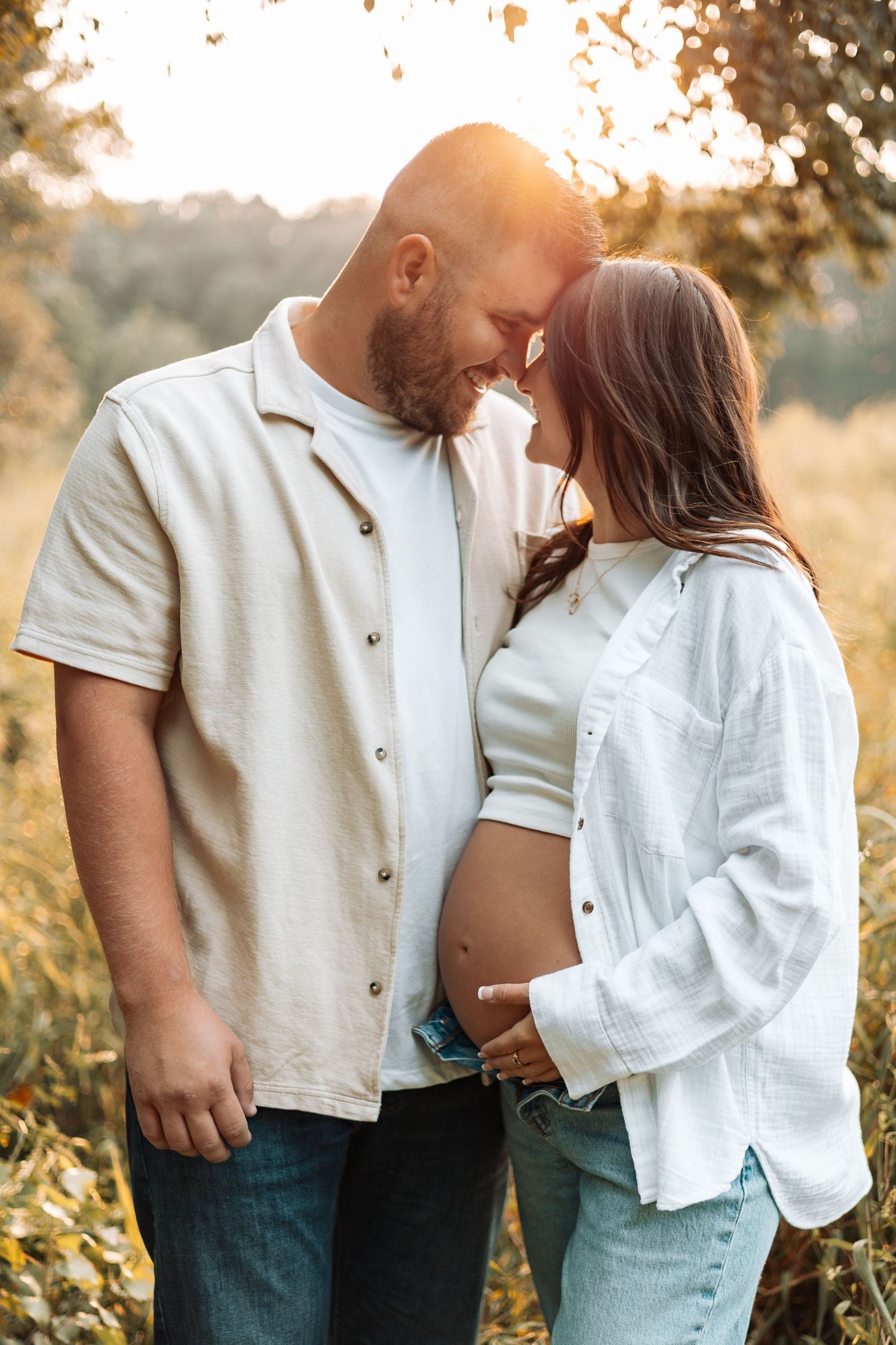 Intimate couple portraits in white outfits during golden hour in a meadow.