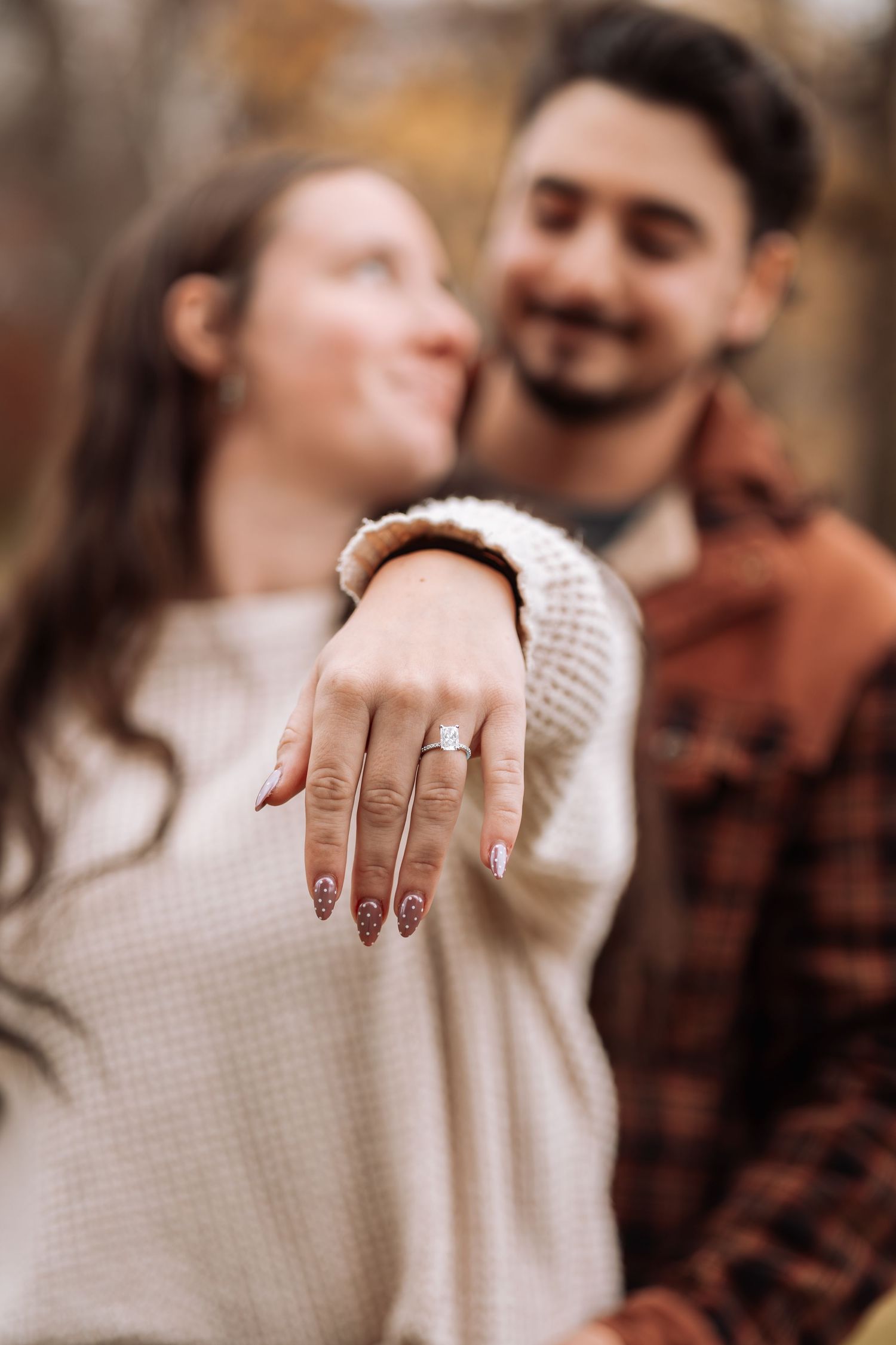Close-up of an engagement ring on hand with cozy sweater in warm autumn tones.