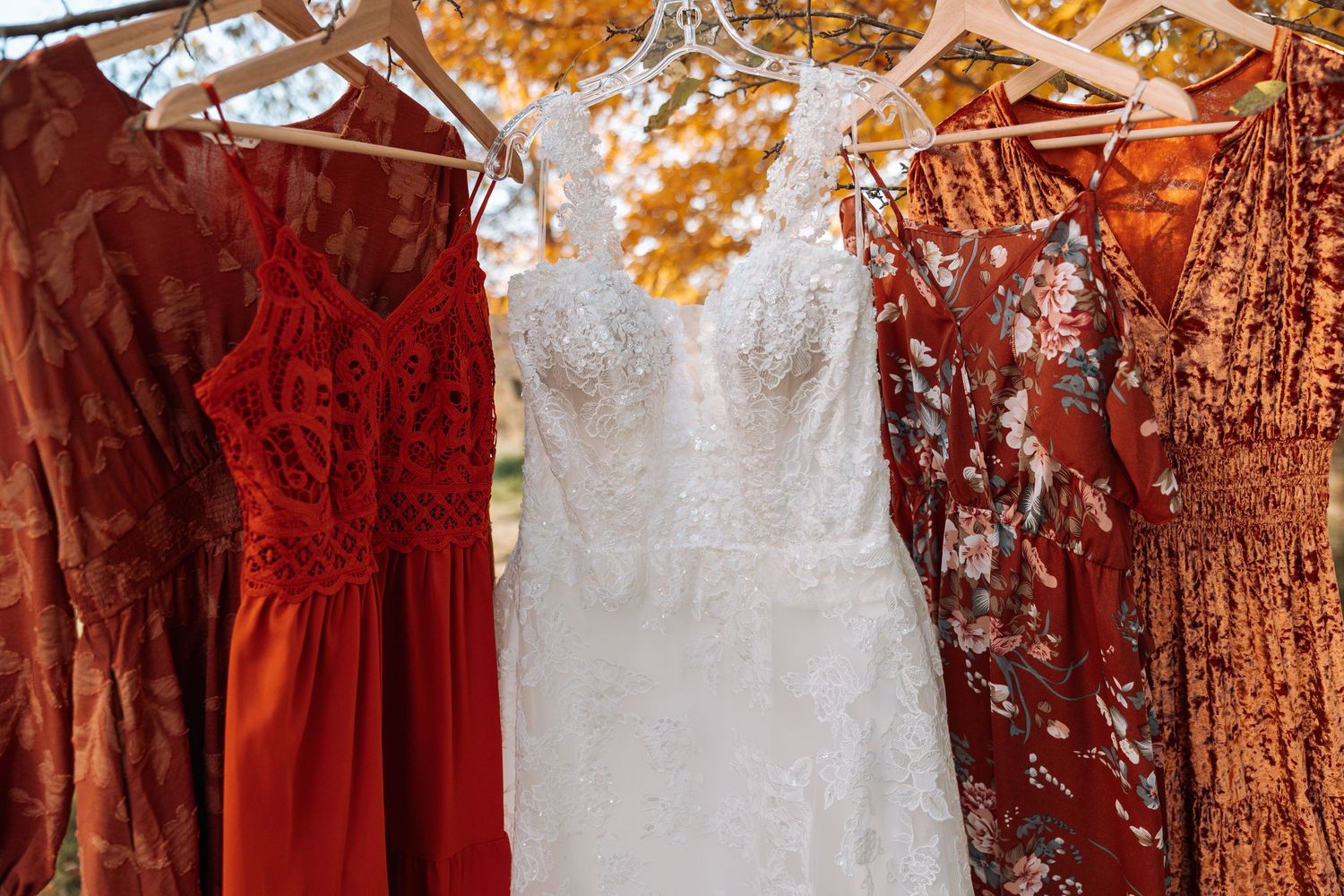 Wedding dresses in white and autumn colors hanging together showing fall wedding color palette.