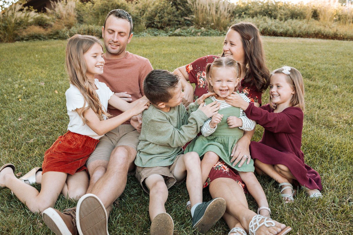 Family sitting together on grass during casual outdoor photo session.