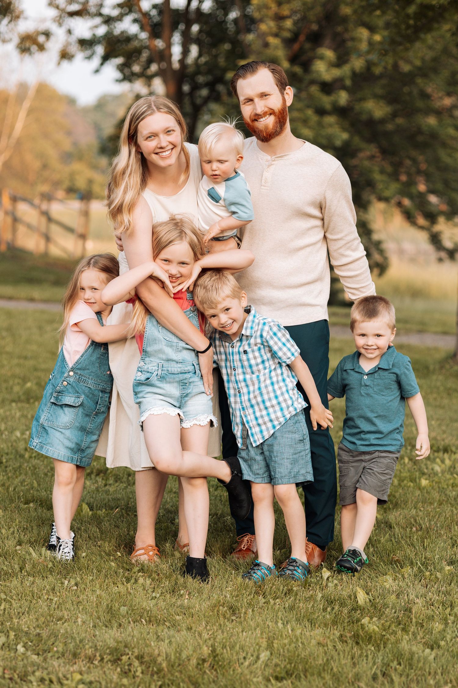 Family playing and laughing together on grassy field during summer photoshoot.