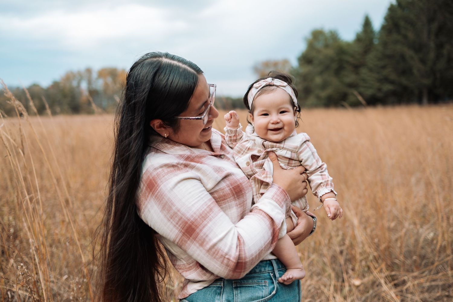 Family members sitting together in tall autumn grass during outdoor photoshoot.