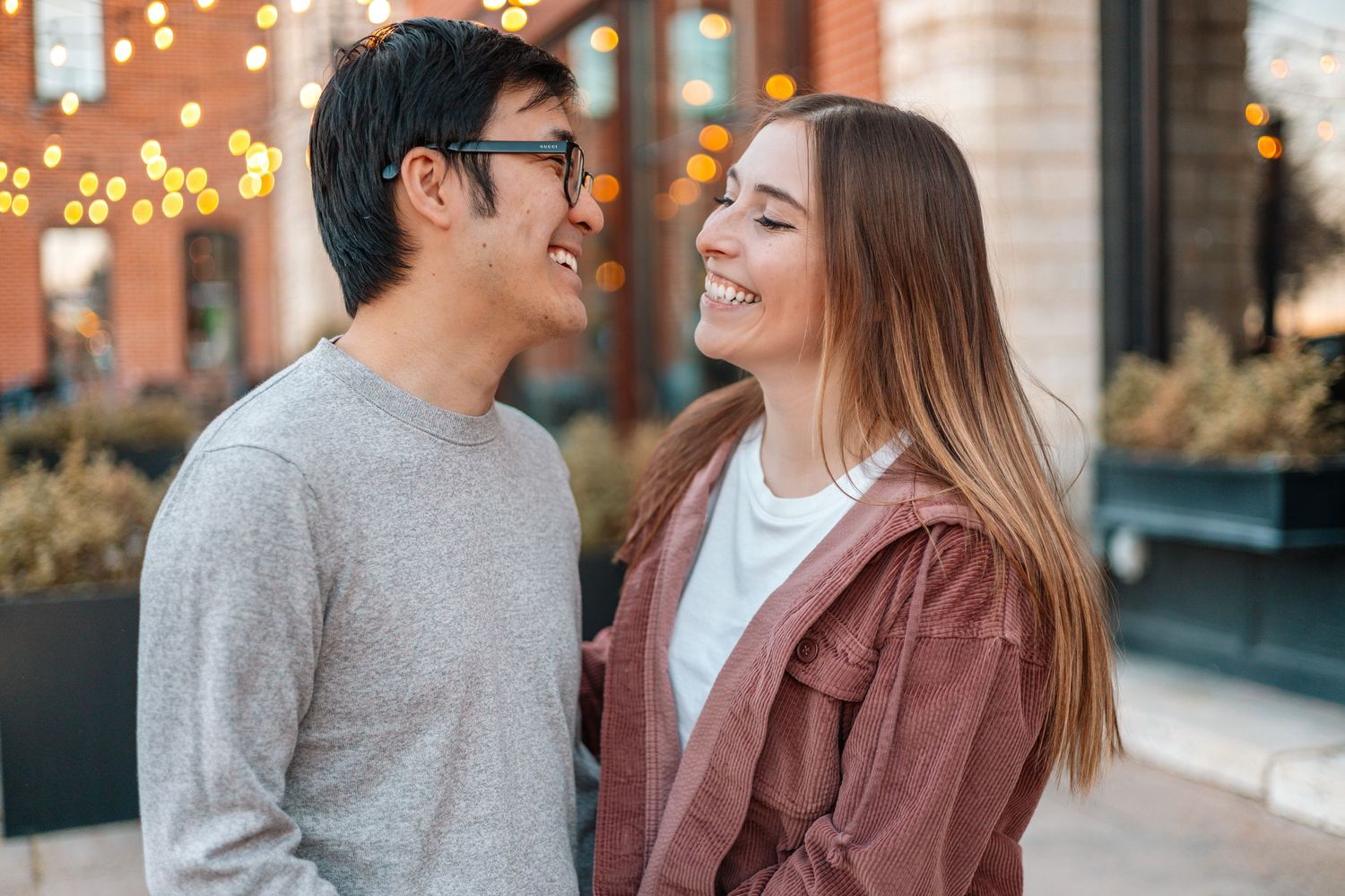 Romantic couple moment with twinkling lights and urban architecture in the background.