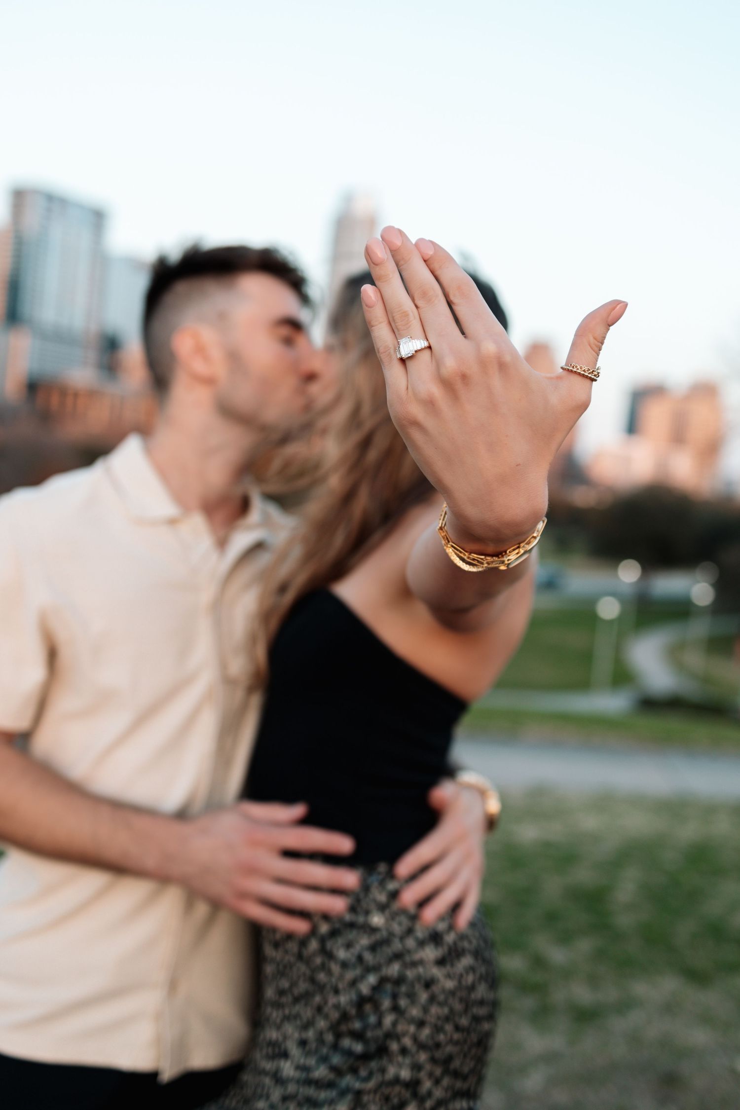 Engagement ring shown with city skyline in background during sunset.