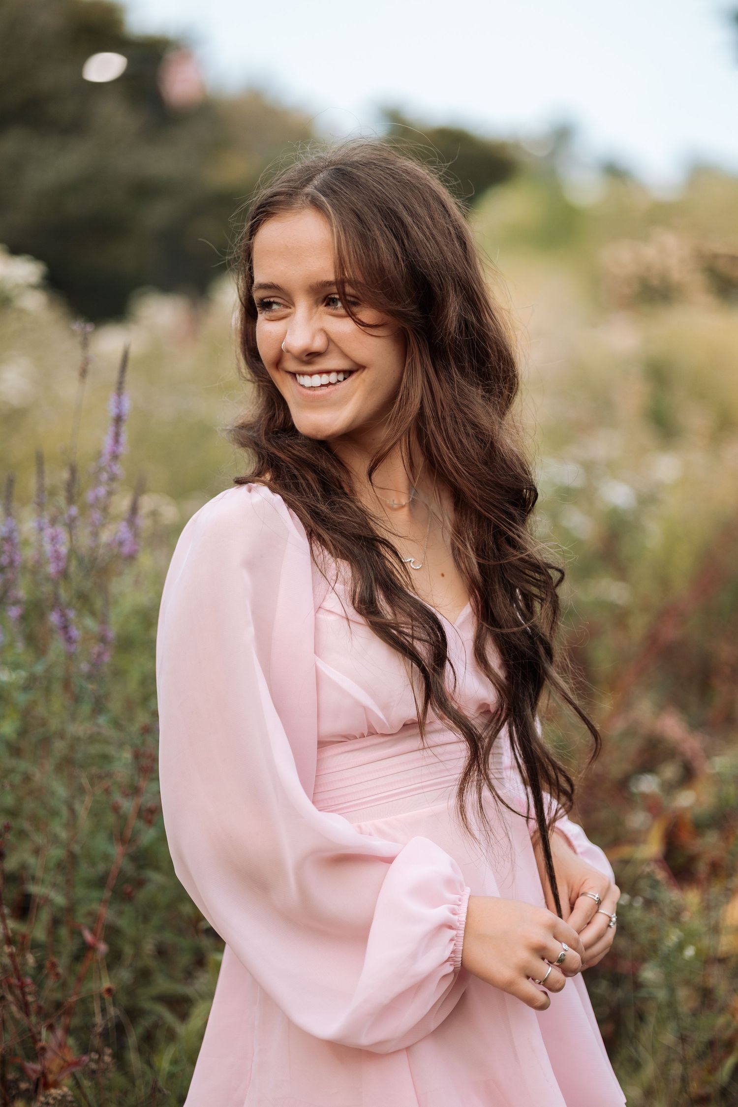 Joyful outdoor portraits in a pink dress with puff sleeves among blooming flowers.