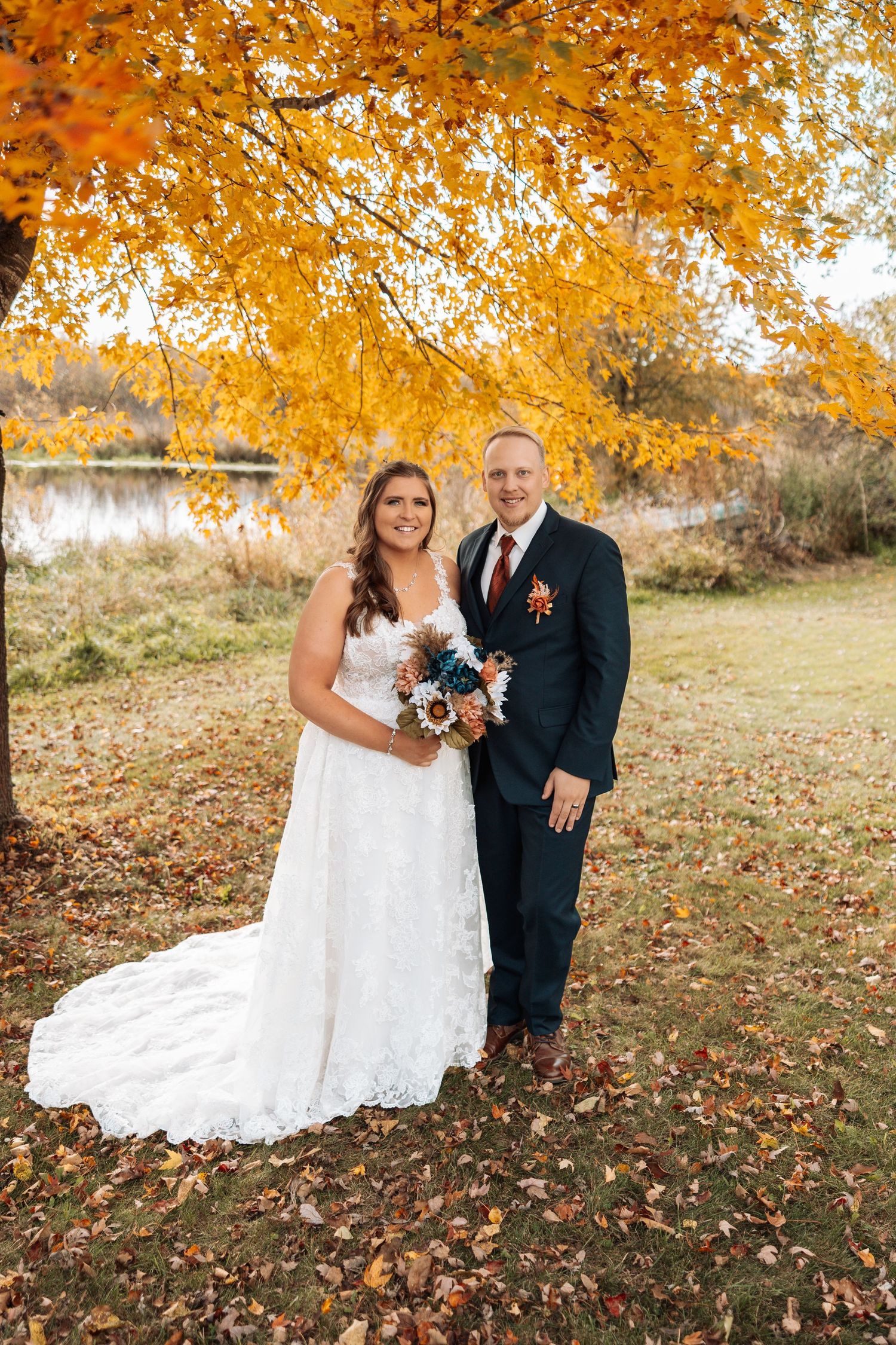 Fall wedding portraits under golden leaves with white dress and navy suit.