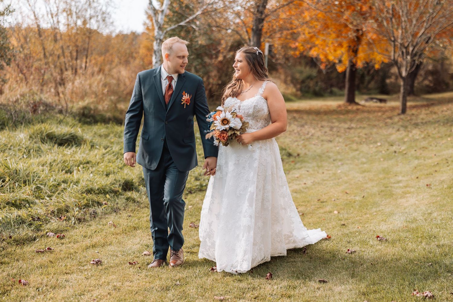 Wedding photography session in a scenic outdoor setting with golden fall leaves.