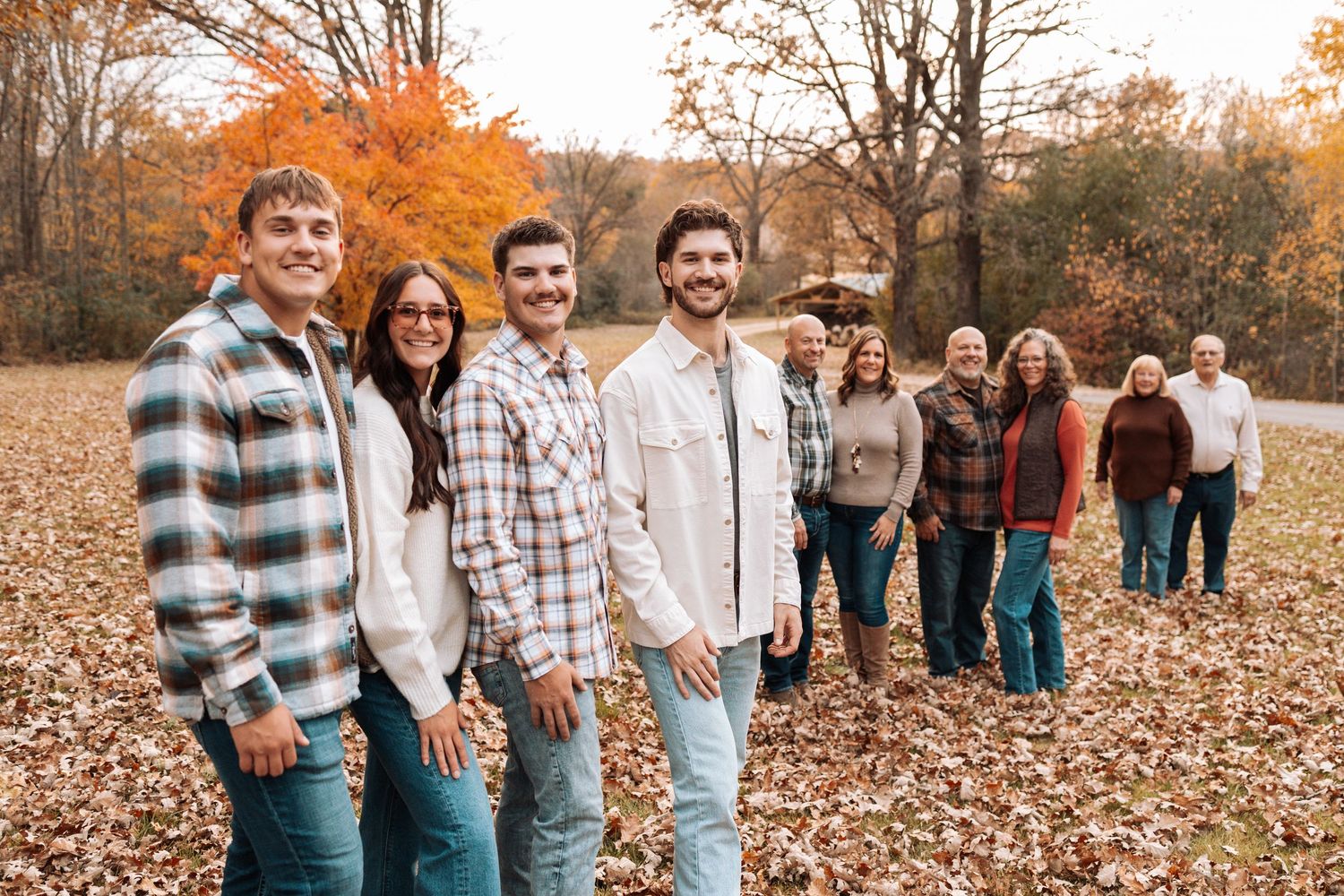 Group photo session in a park with fallen autumn leaves covering the ground.