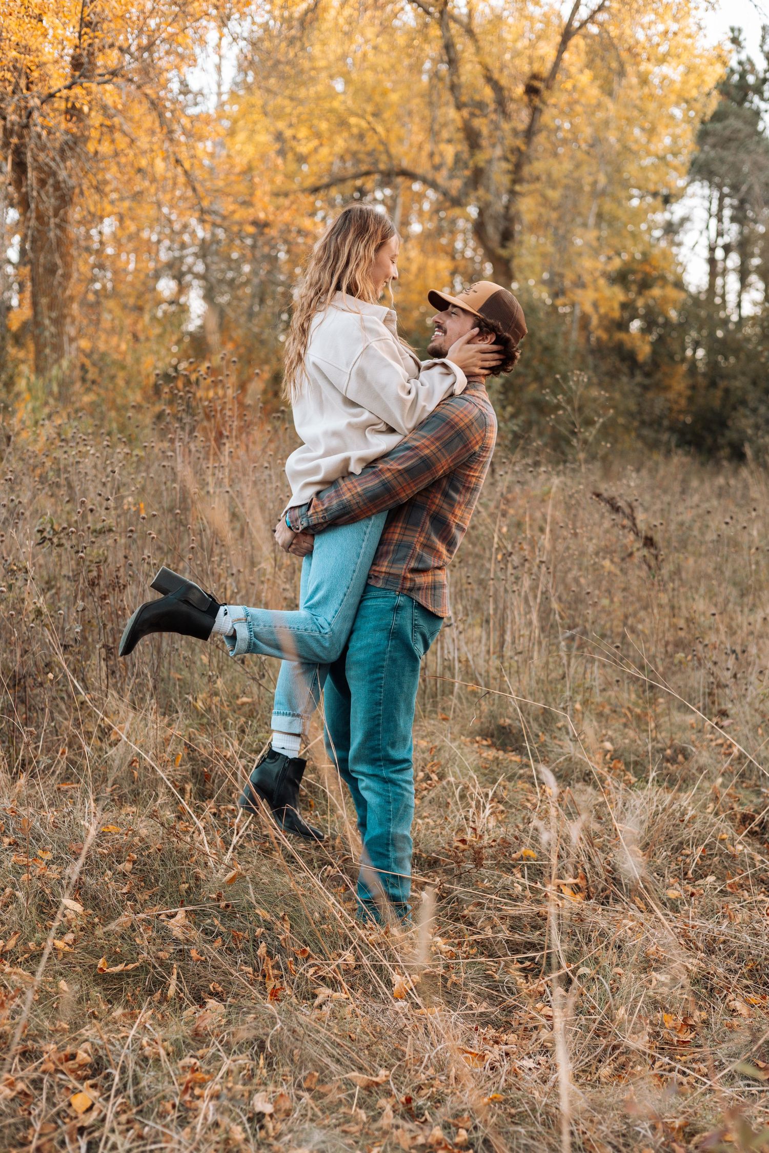 Couple embracing on autumn trail surrounded by golden foliage.