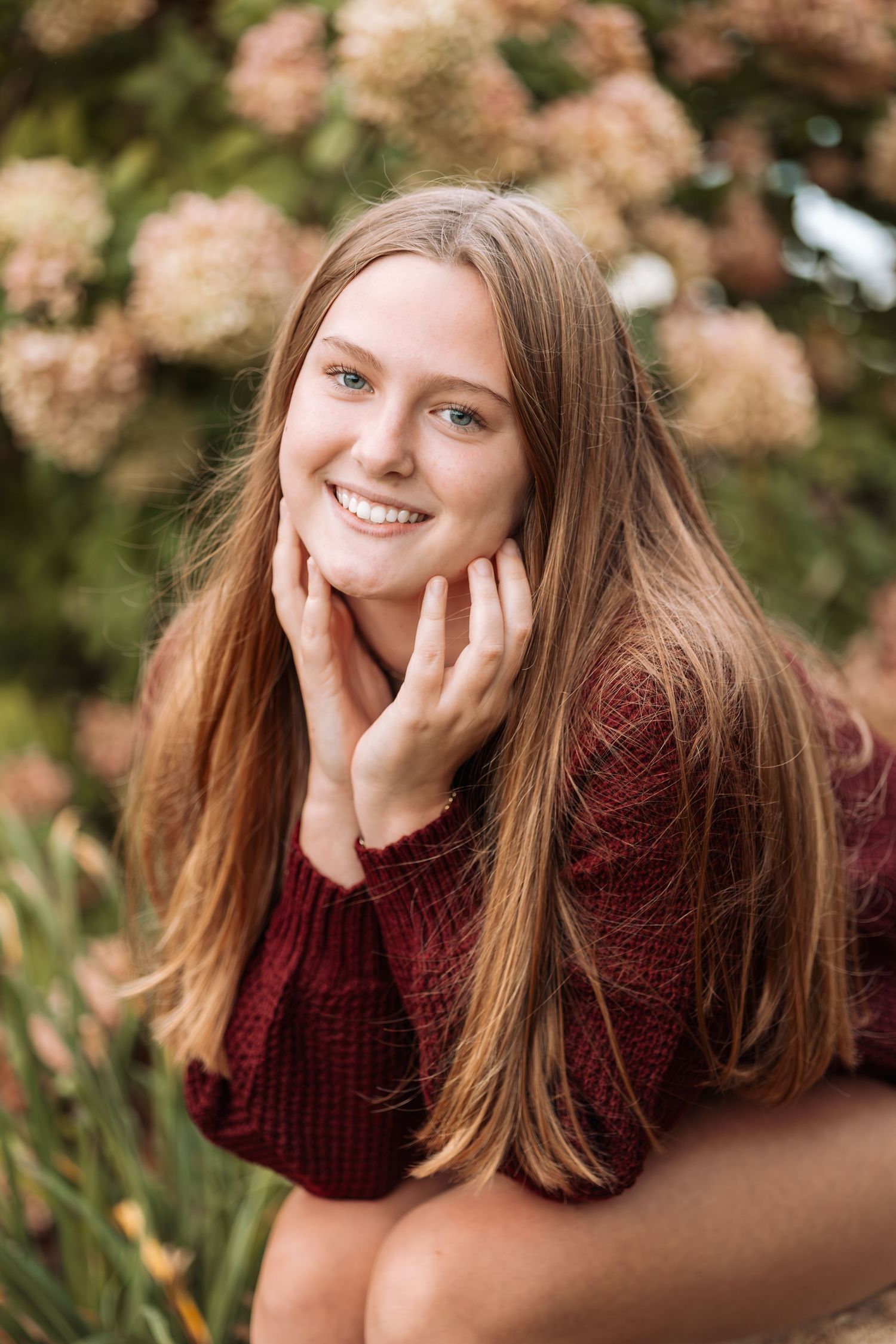 Person in burgundy sweater posing playfully during fall photo session.