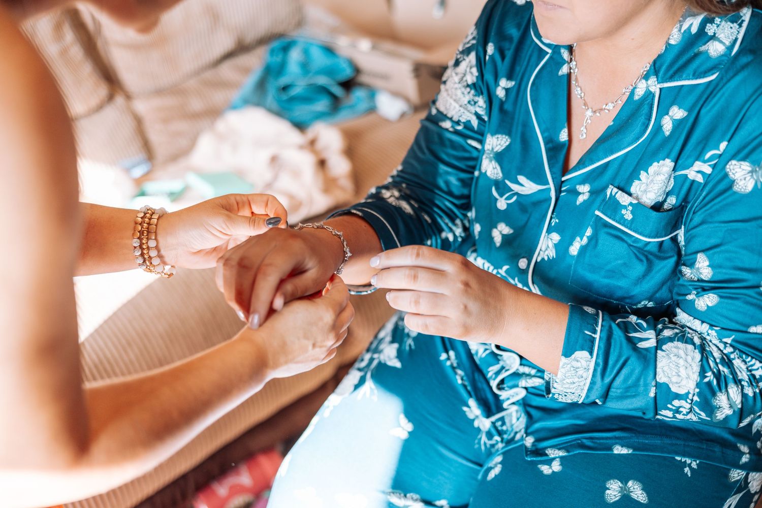 Hands exchanging rings during wedding preparation in morning light.