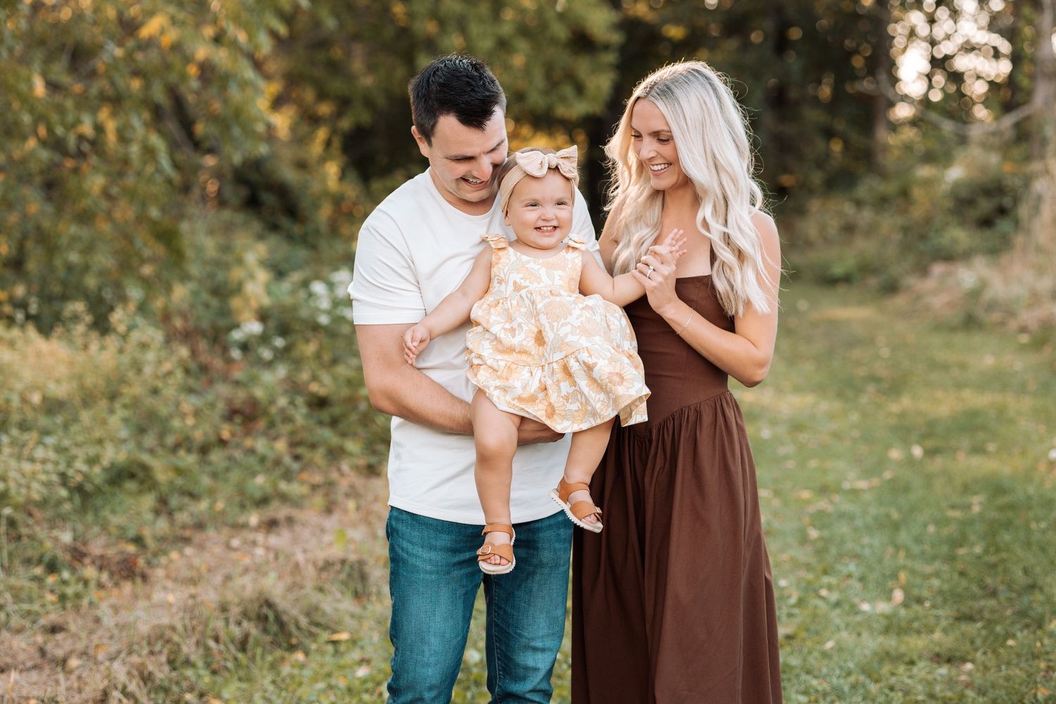 Family walking together in a grassy field during golden hour.