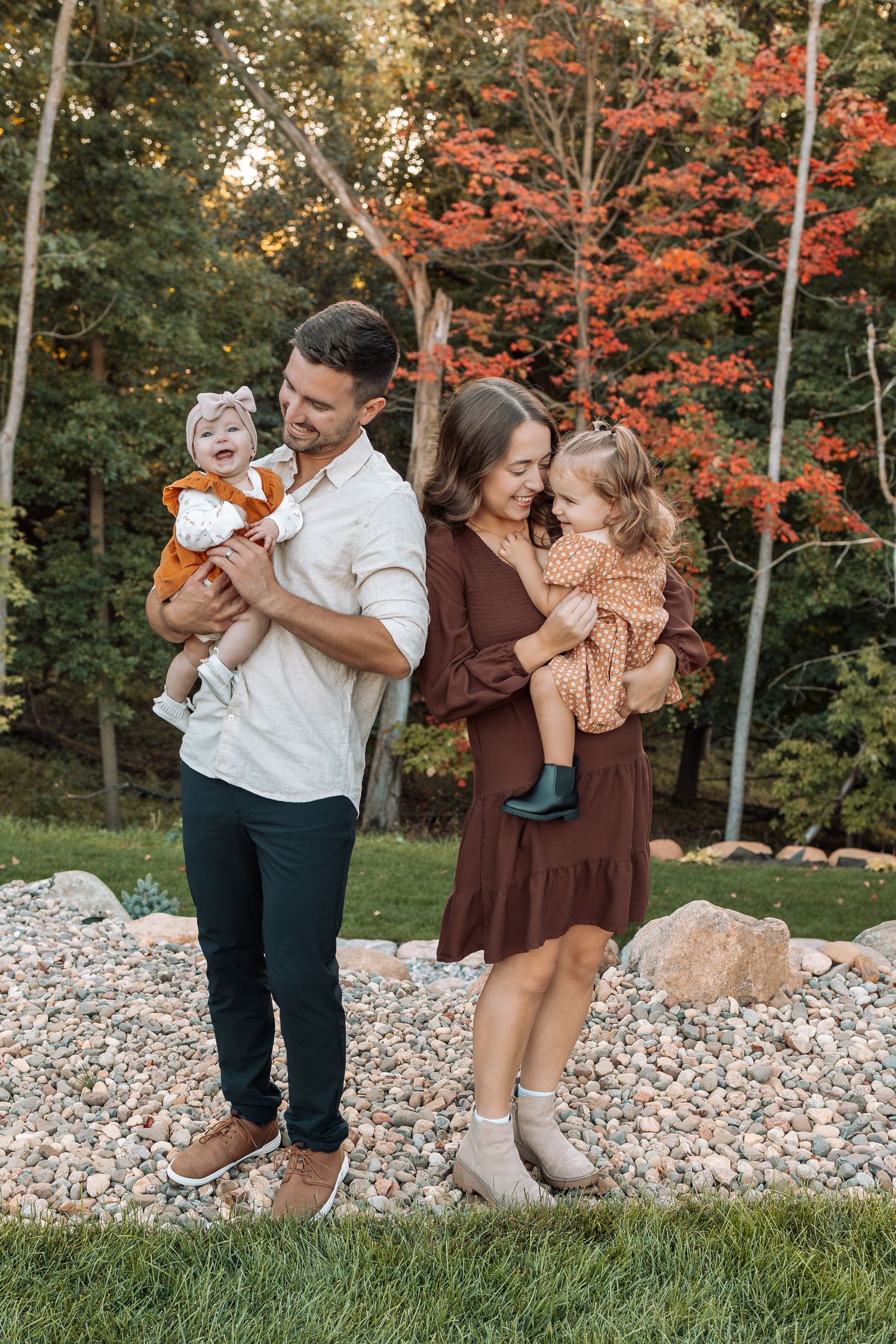 Family laughing together during outdoor photoshoot with vibrant fall colors.