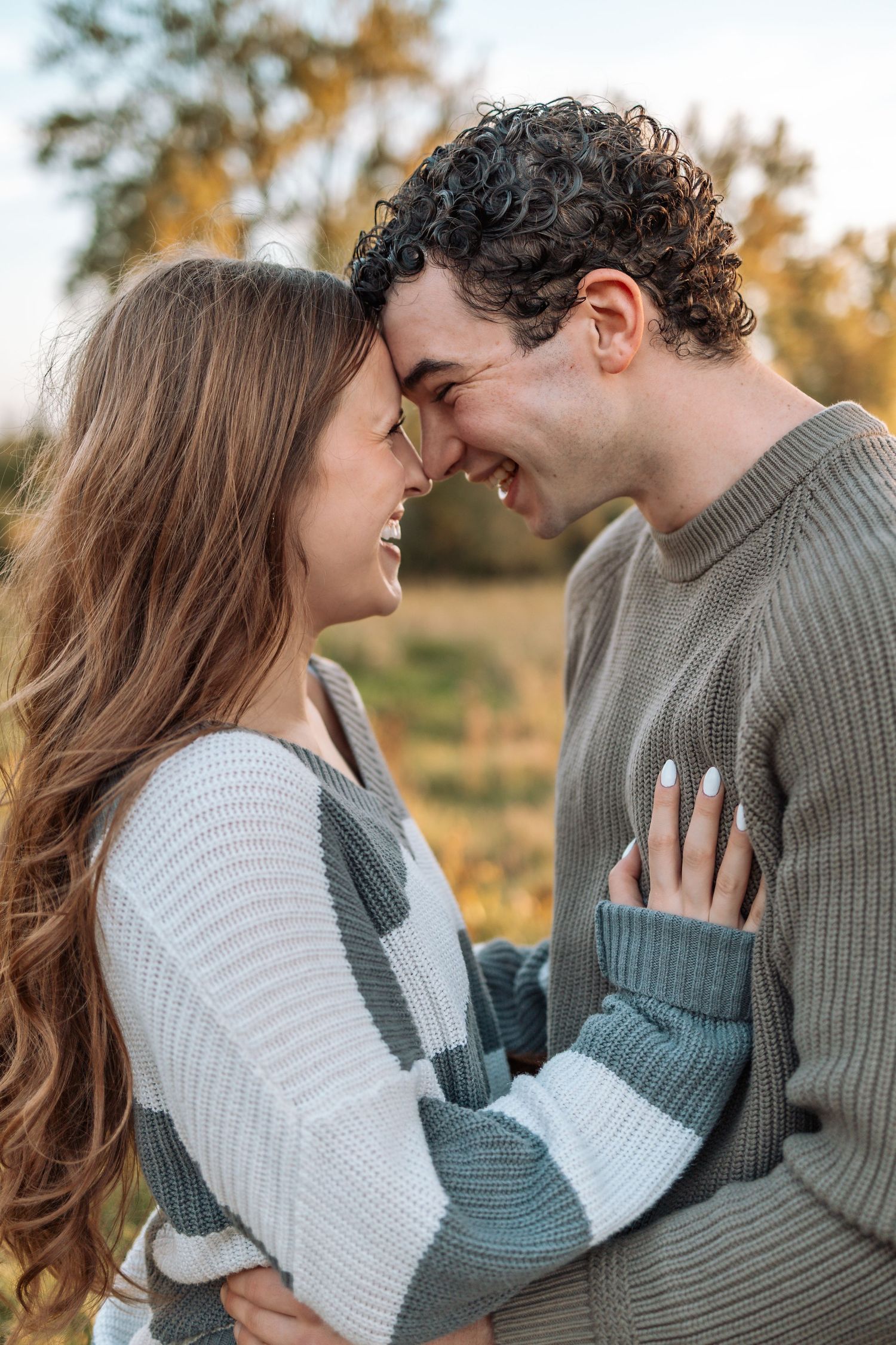 Romantic couple in sweaters sharing intimate moments during autumn outdoor photoshoot.