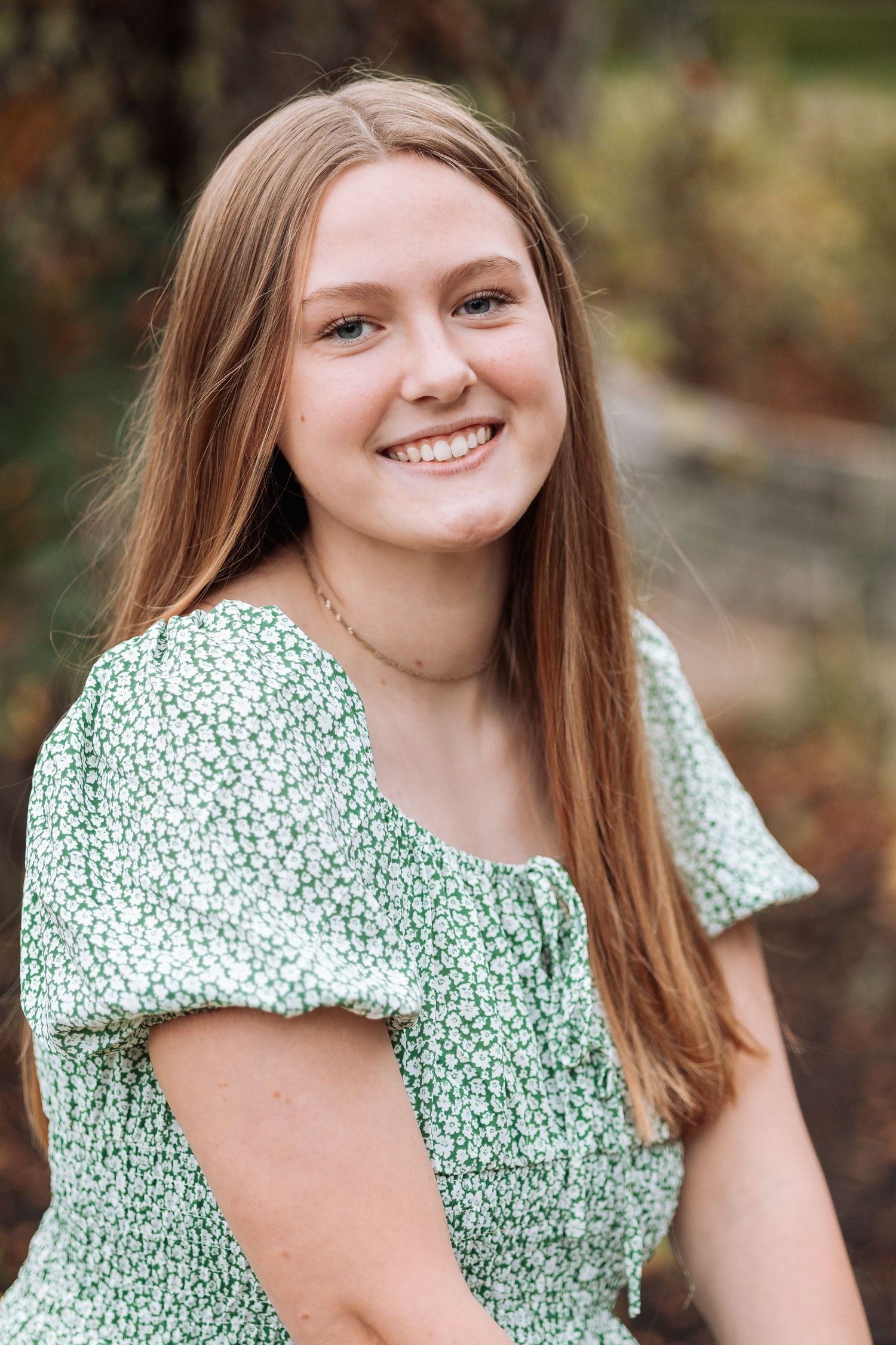 Person wearing mint green floral dress during outdoor portrait session.