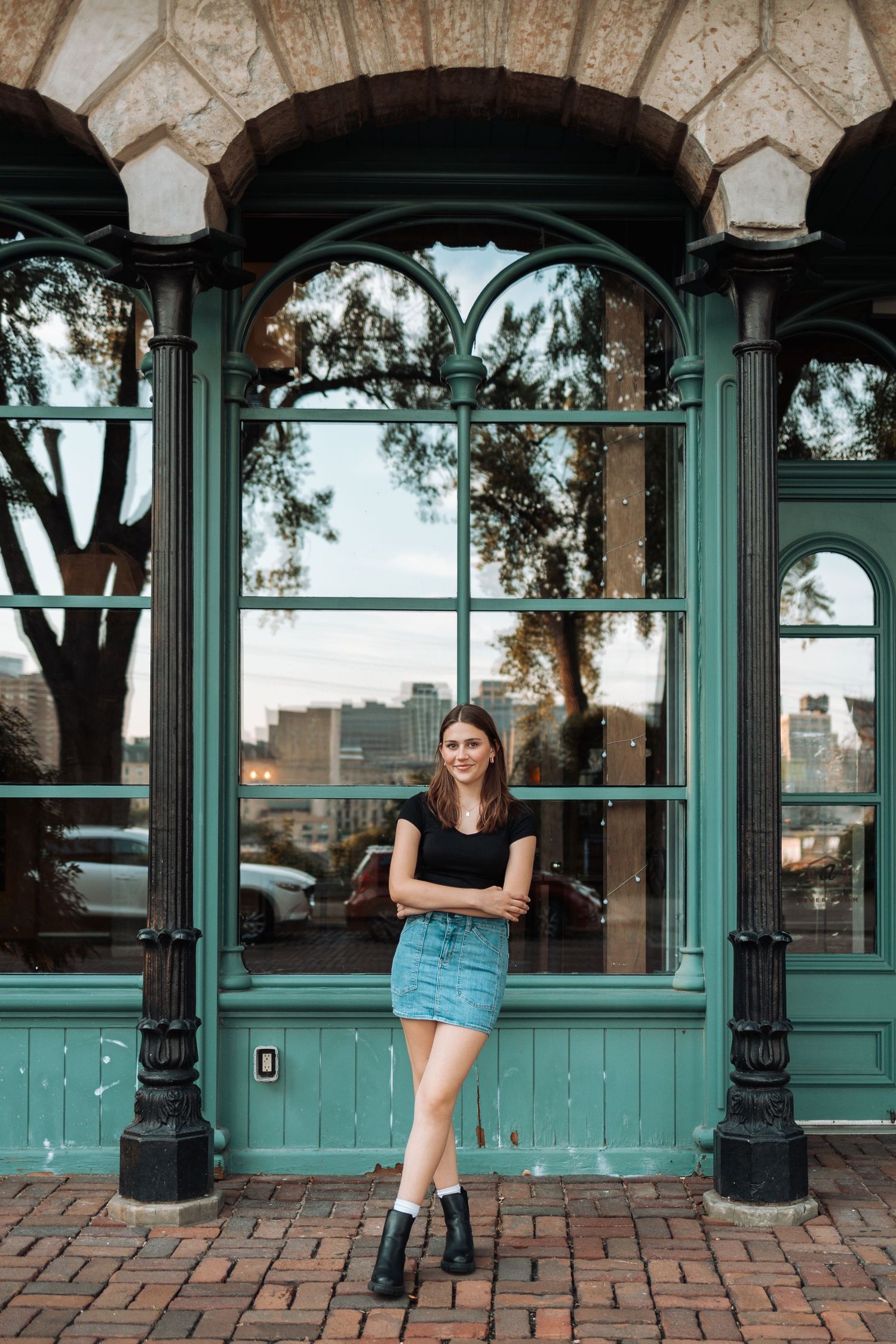 Black outfit styled against green vintage storefront with arched windows with Kenzie Ayla Images in the Twin Cities MN area.