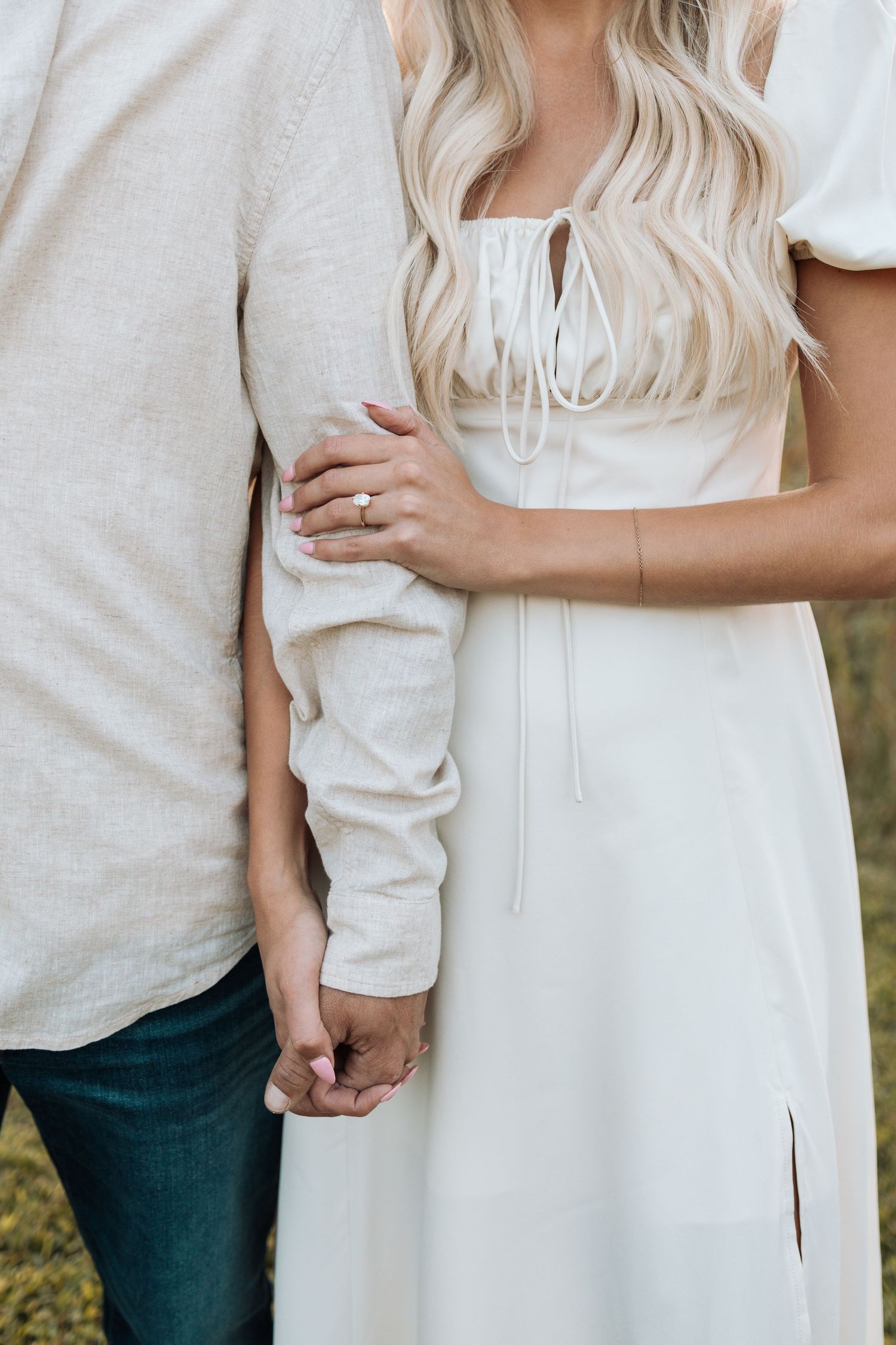 Close-up details of a couple's embrace showing white clothing and gentle hand placement.