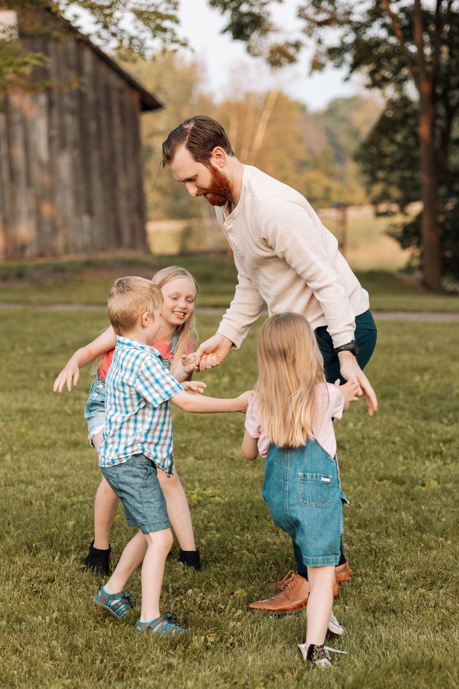 Playful family moment captured outdoors with parents and children running on grass.