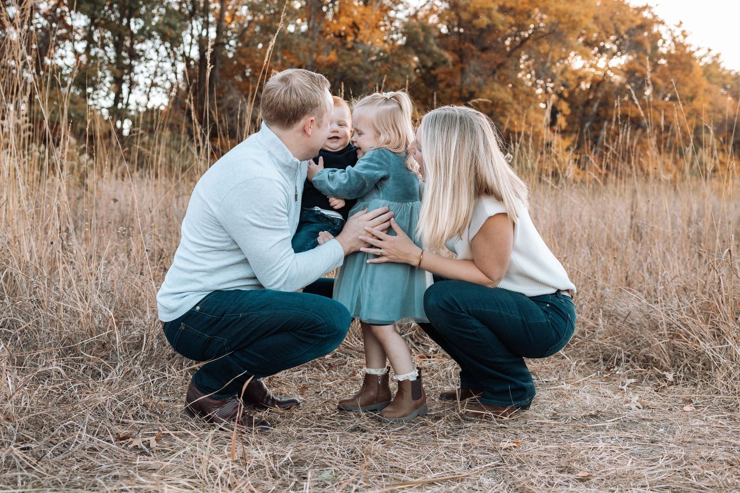 Family sitting together in a rustic field during golden hour with autumn colors.