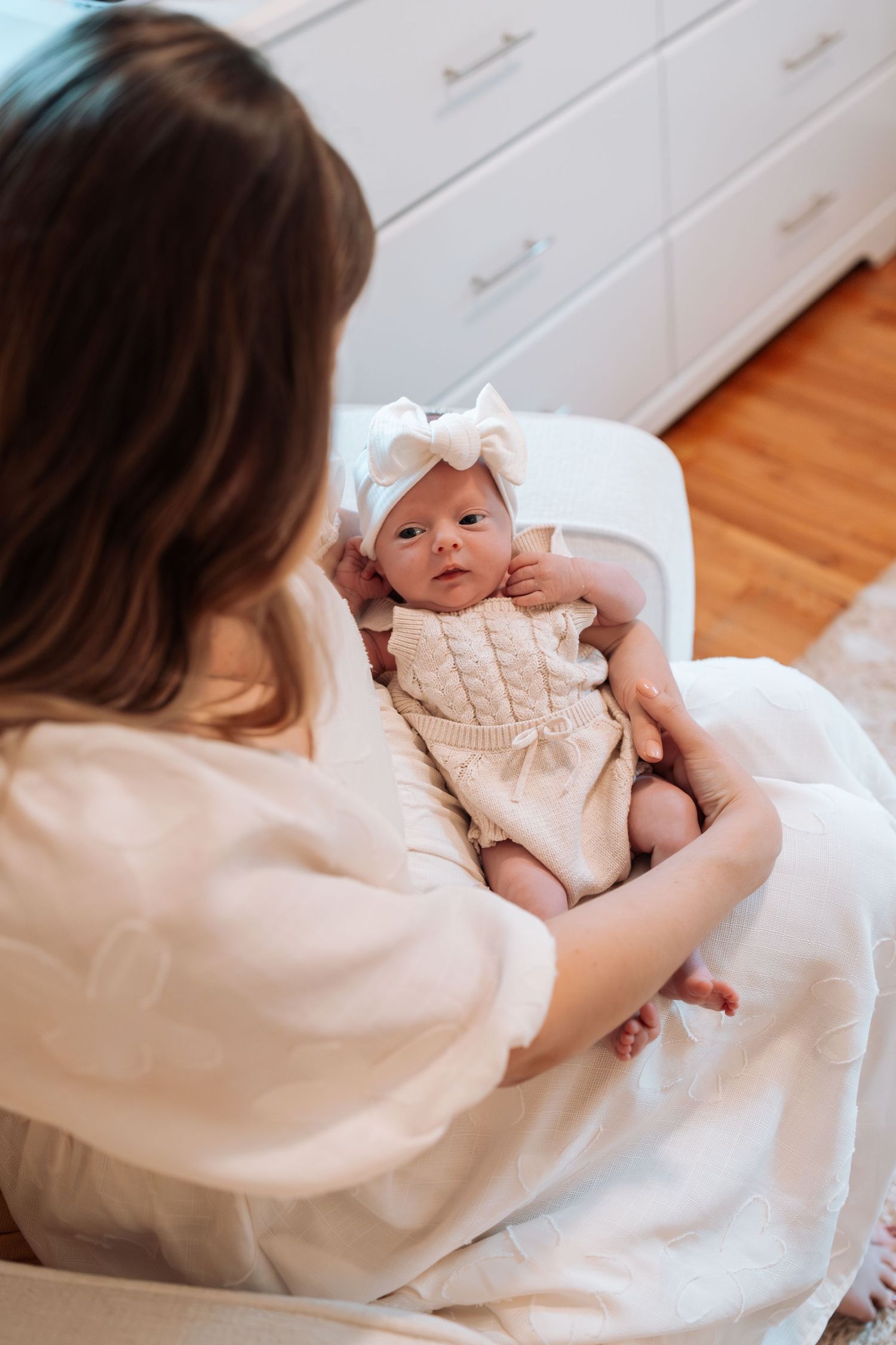 Intimate indoor portrait session with baby on white bedding.
