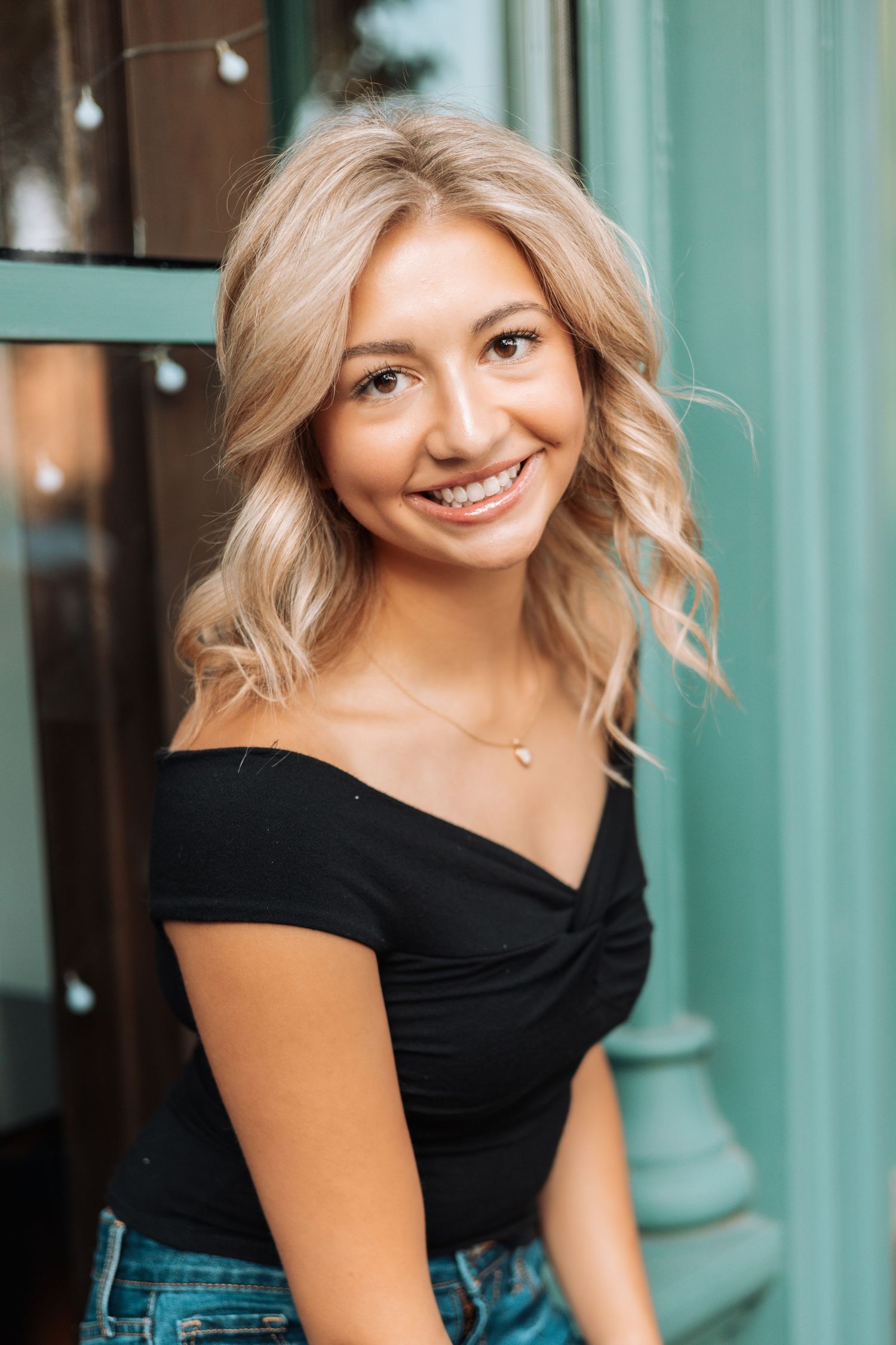 Portrait of a person wearing a black off-shoulder top with wavy blonde hair with Kenzie Ayla Images in the Twin Cities MN area.