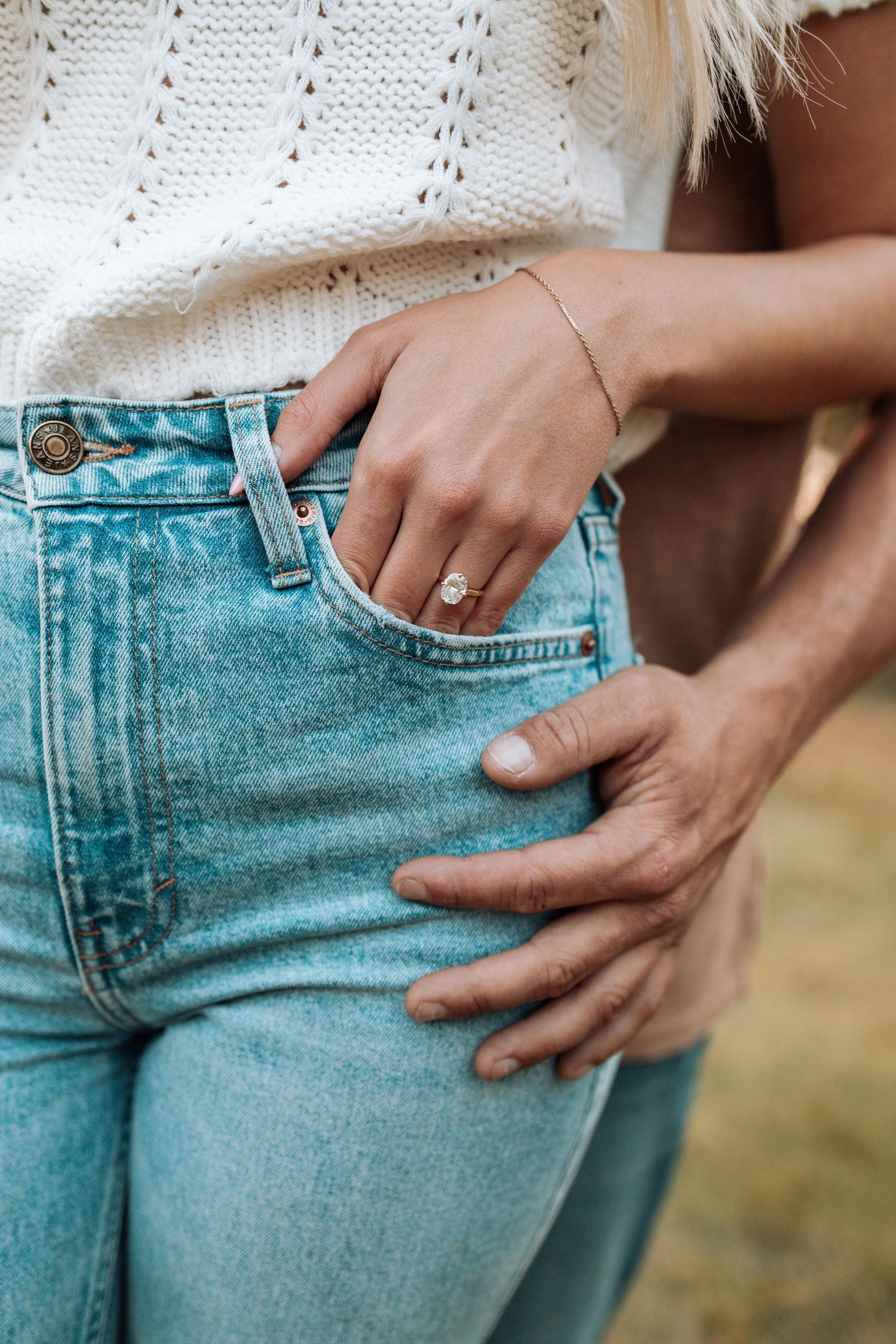 Close-up detail shot of light blue denim jeans and a white knit sweater.