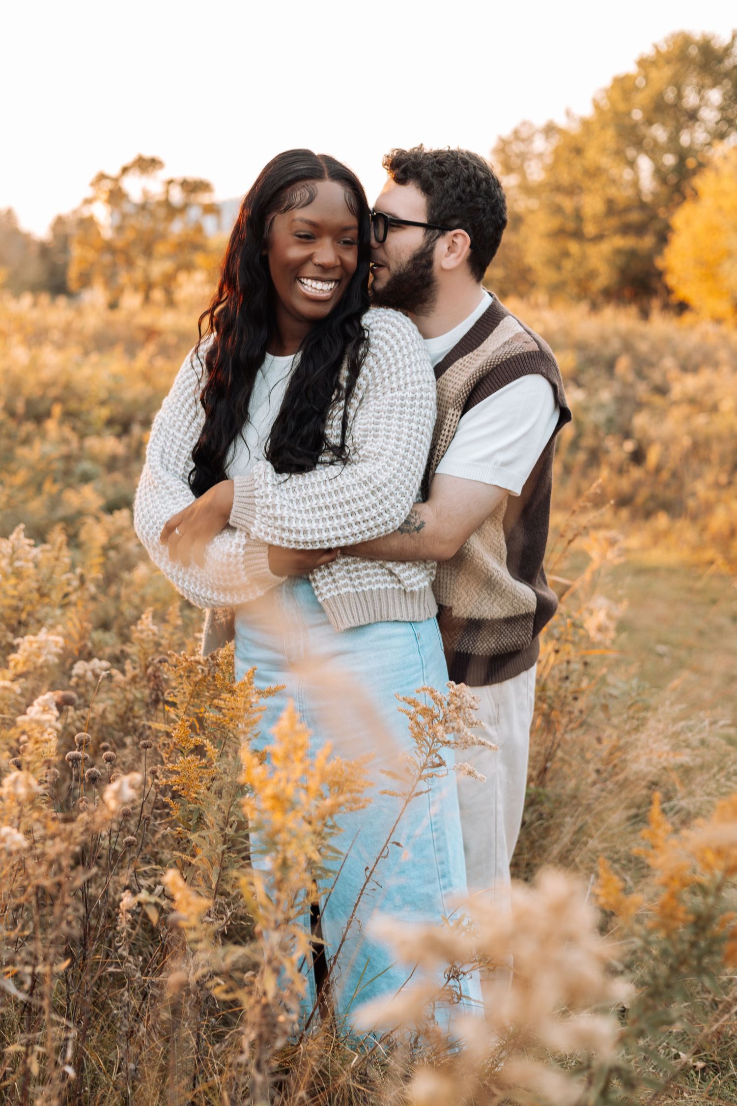 Romantic couple portrait in a sunlit field with golden autumn wildflowers.