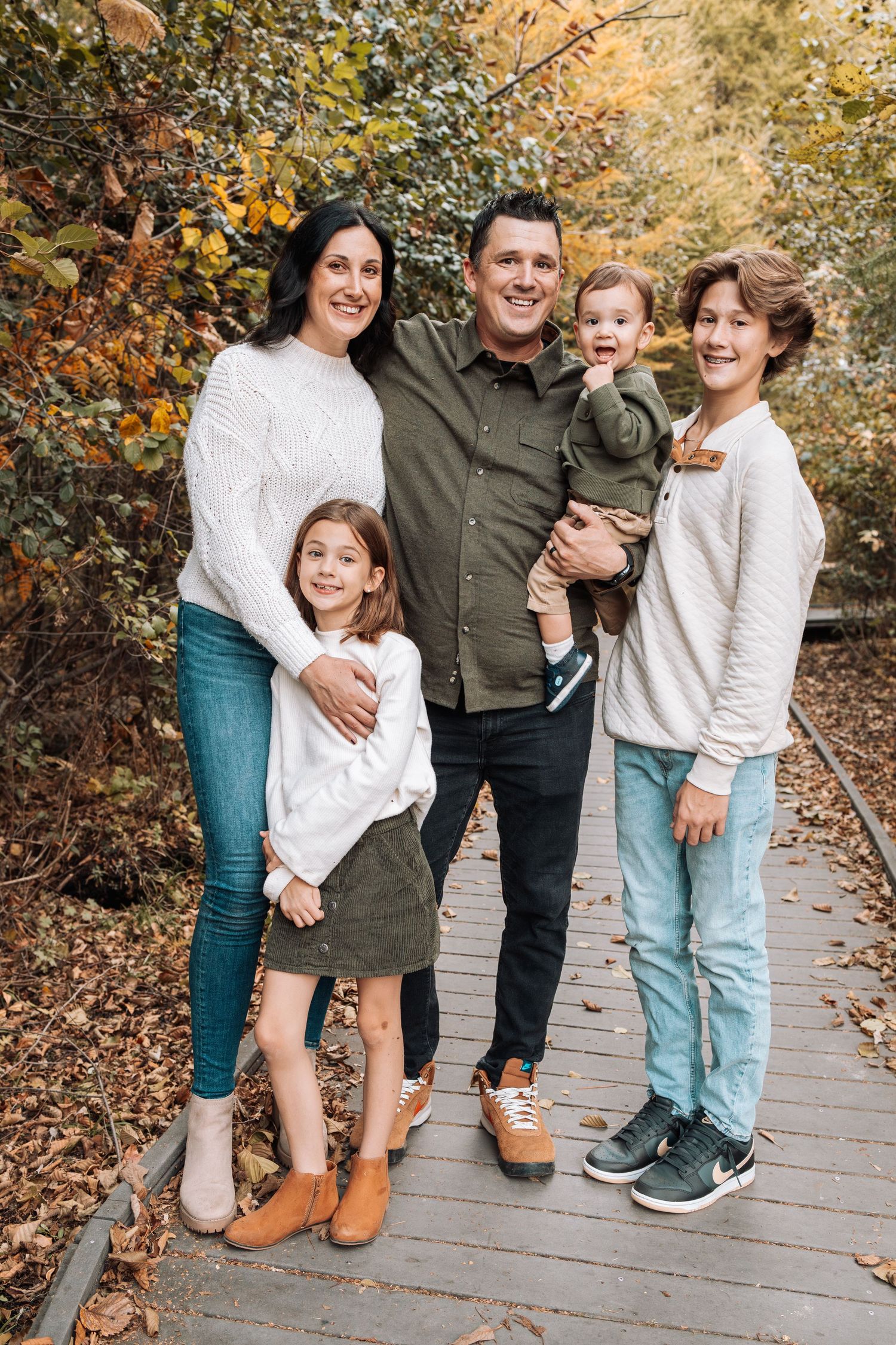 Casual family portrait showing legs and feet standing together on wooden walkway.