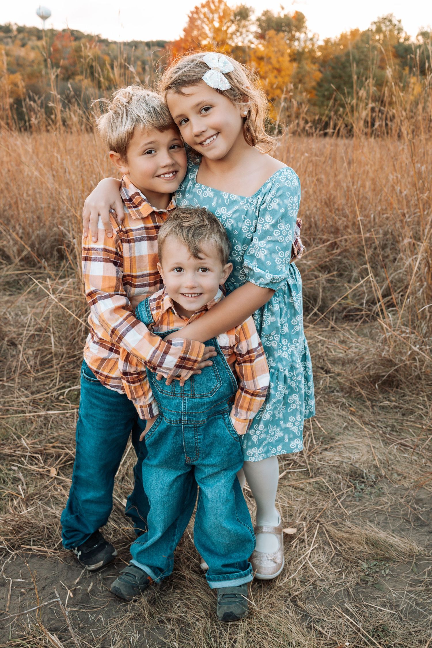 Children playing and laughing together in tall autumn grass at sunset.